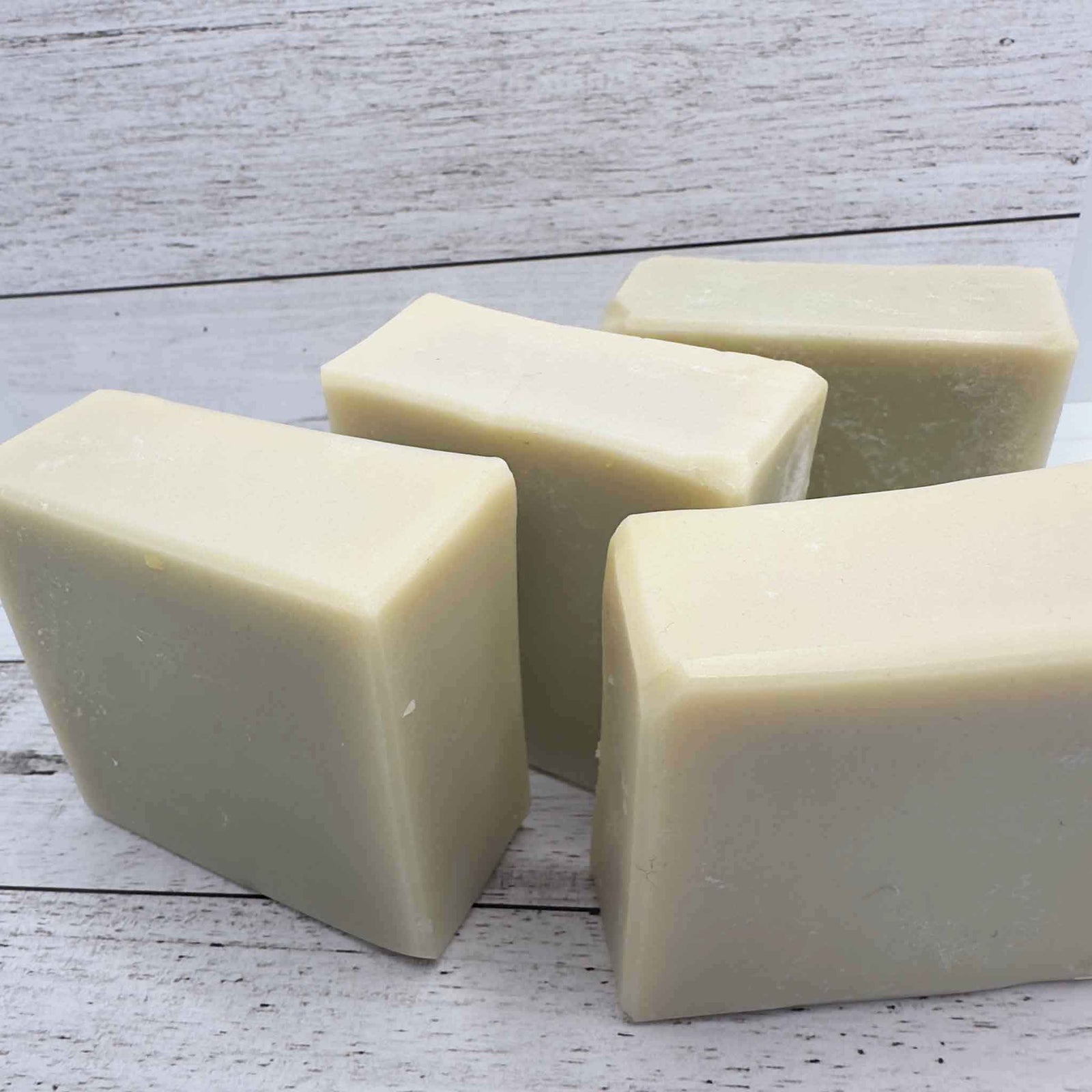 4 square bars of green soap on a timber background