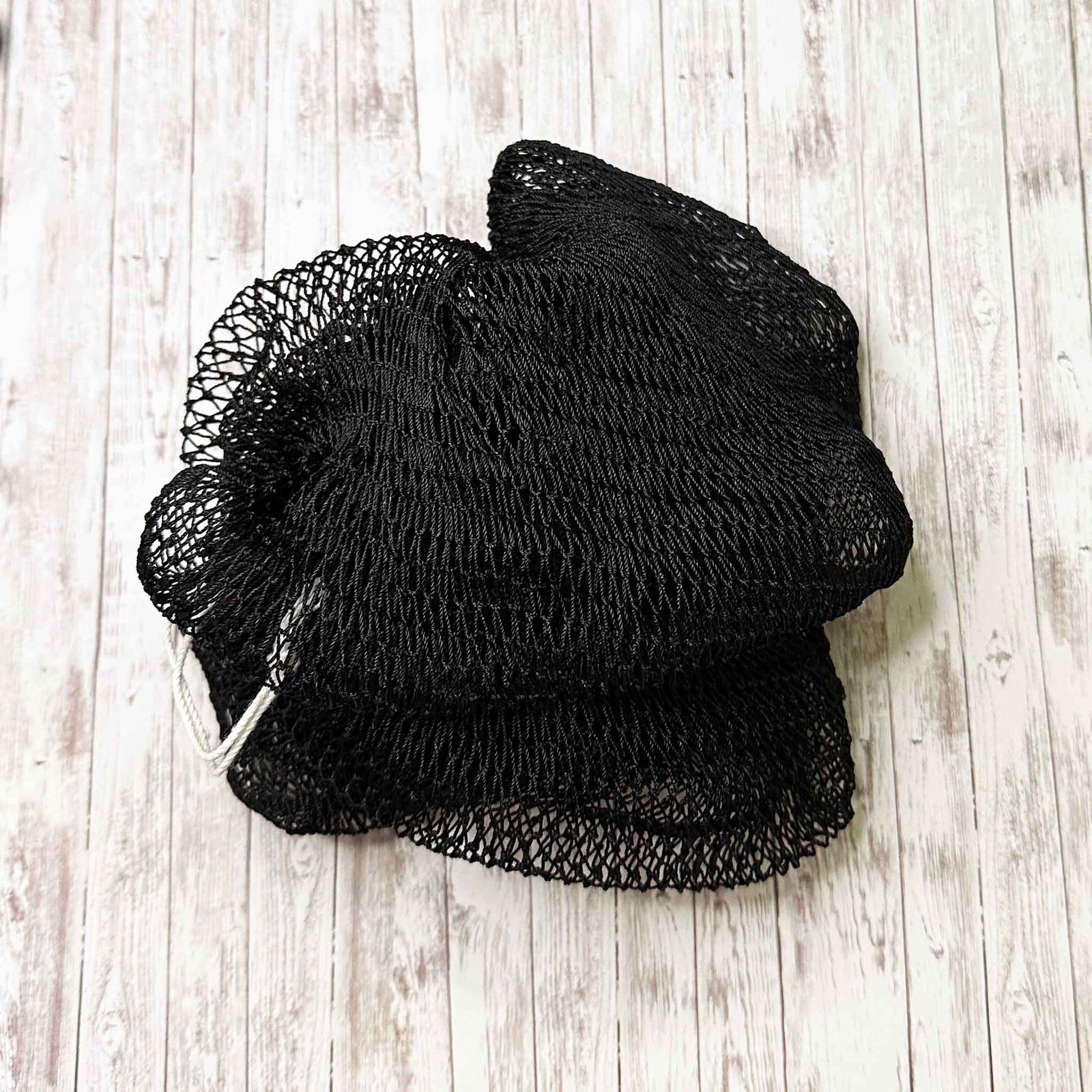 A coil of African Net Sponge coloured Black on a white background