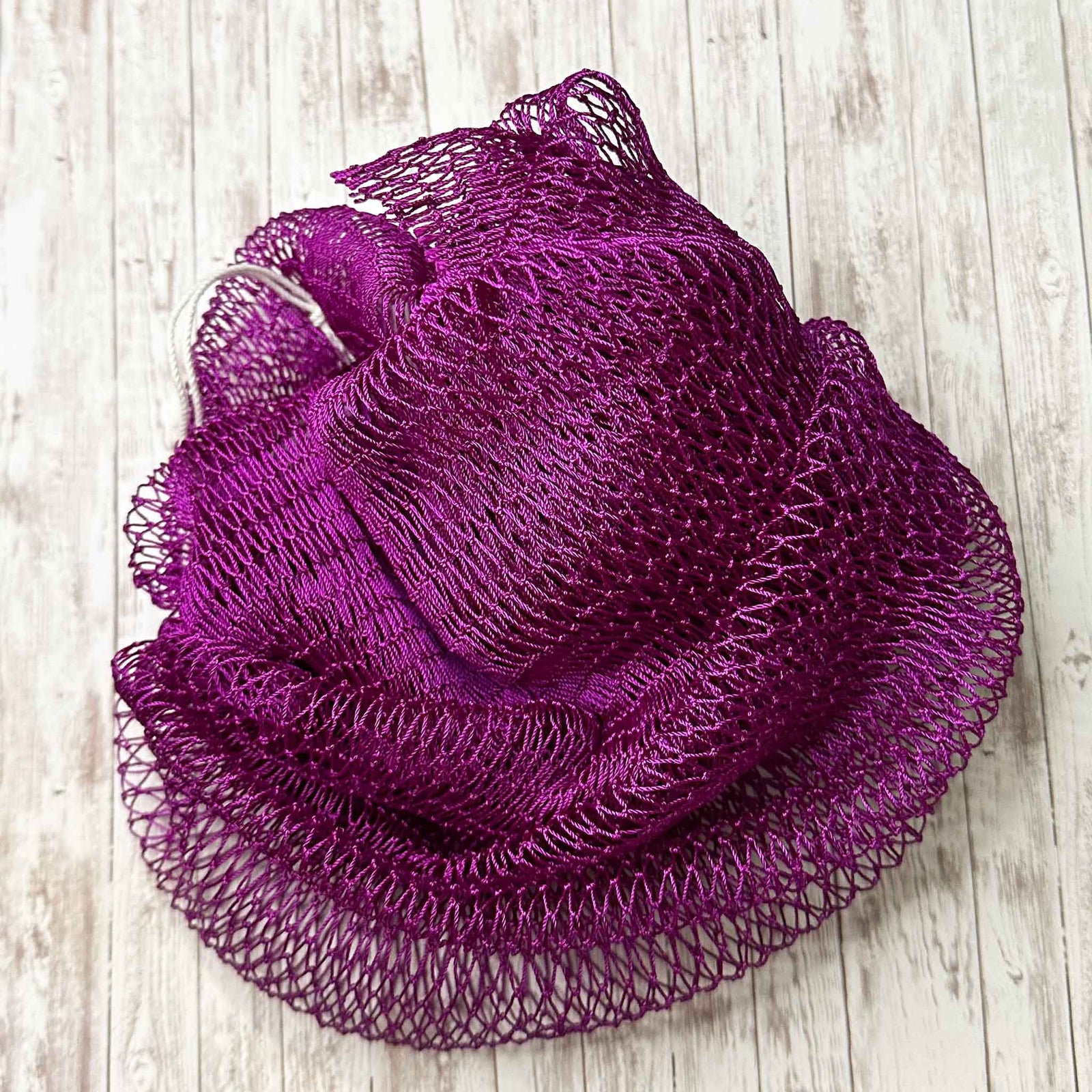 A coil of African Net Sponge coloured Maroon on a white background