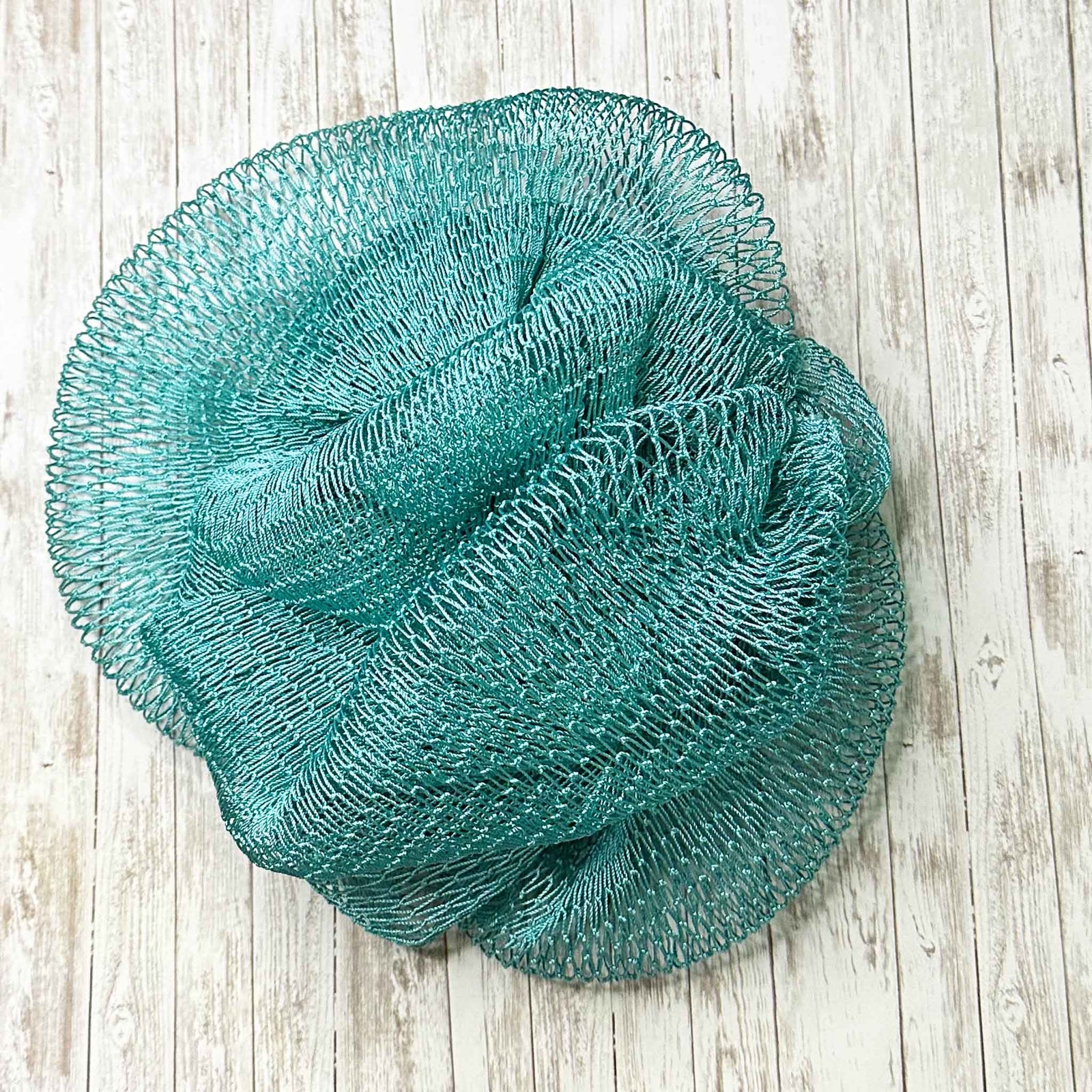 A coil of African Net Sponge coloured Teal on a white background