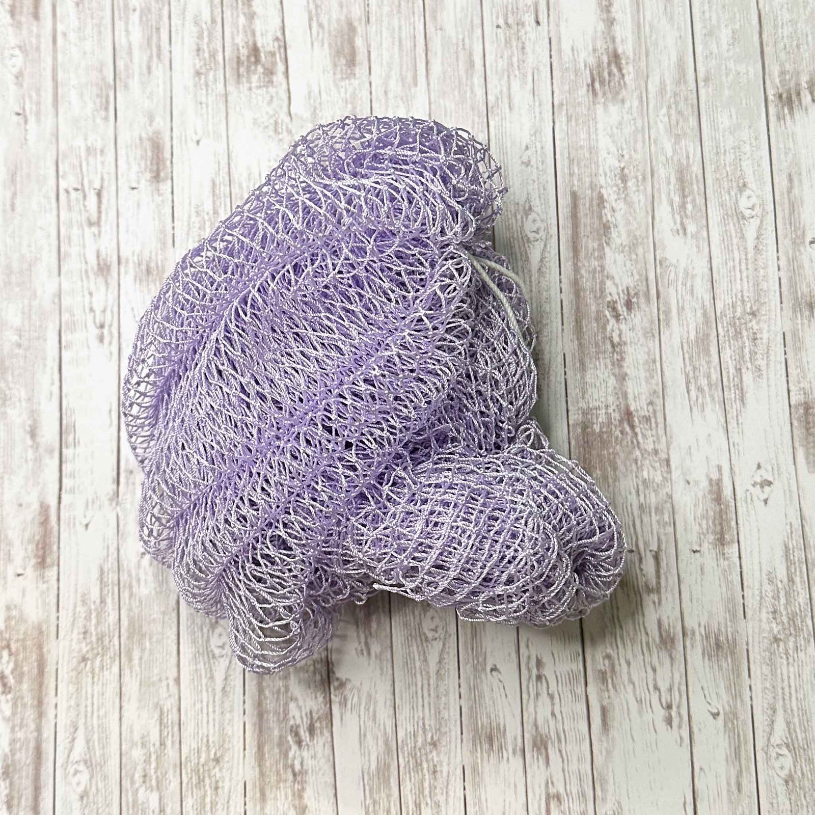 A coil of African Net Sponge coloured Lilac on a white background