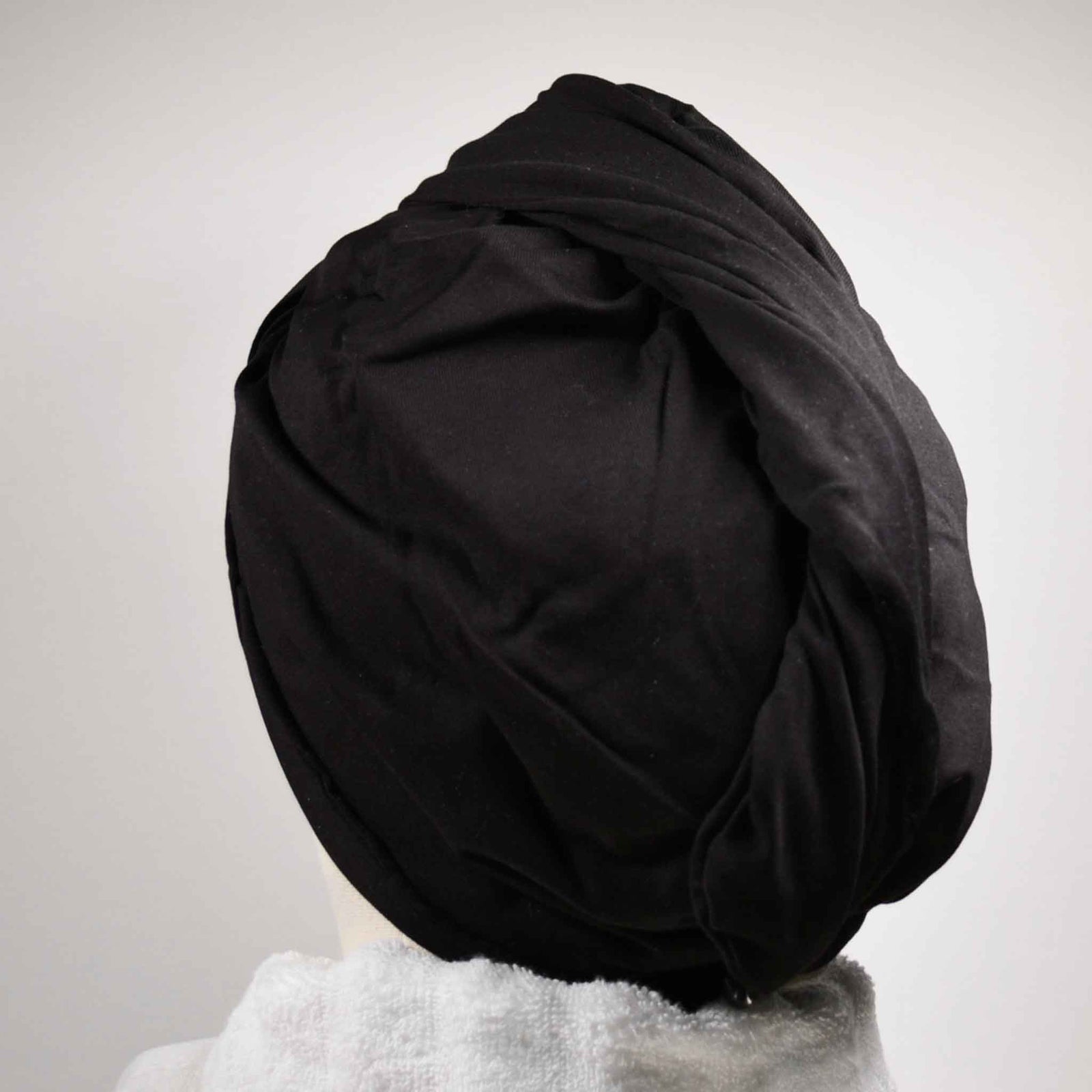 Showing wearing the black hair wrap with white towel round the neck on a white background
