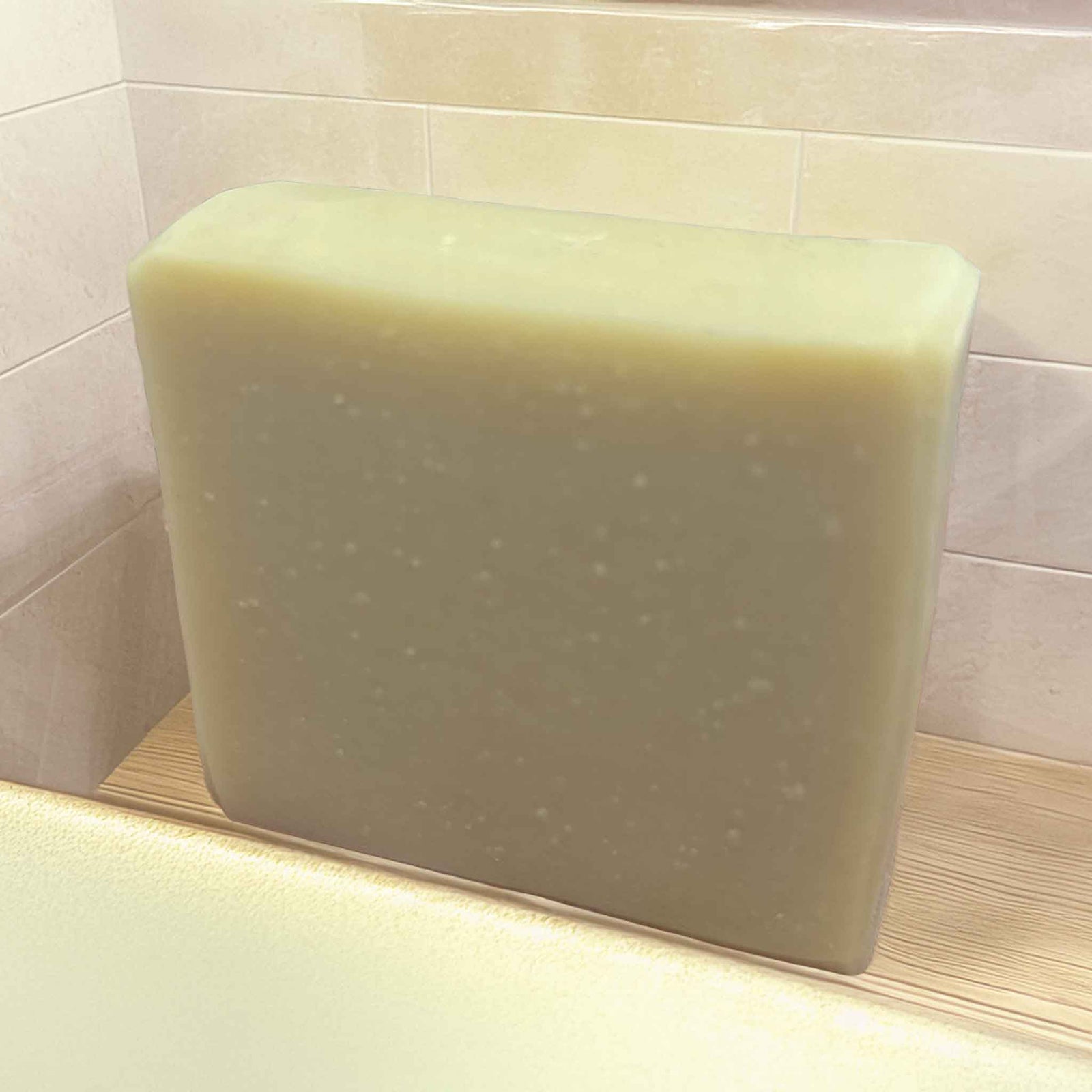 A natural soap, cream coloured on a wood bench with a tiled background