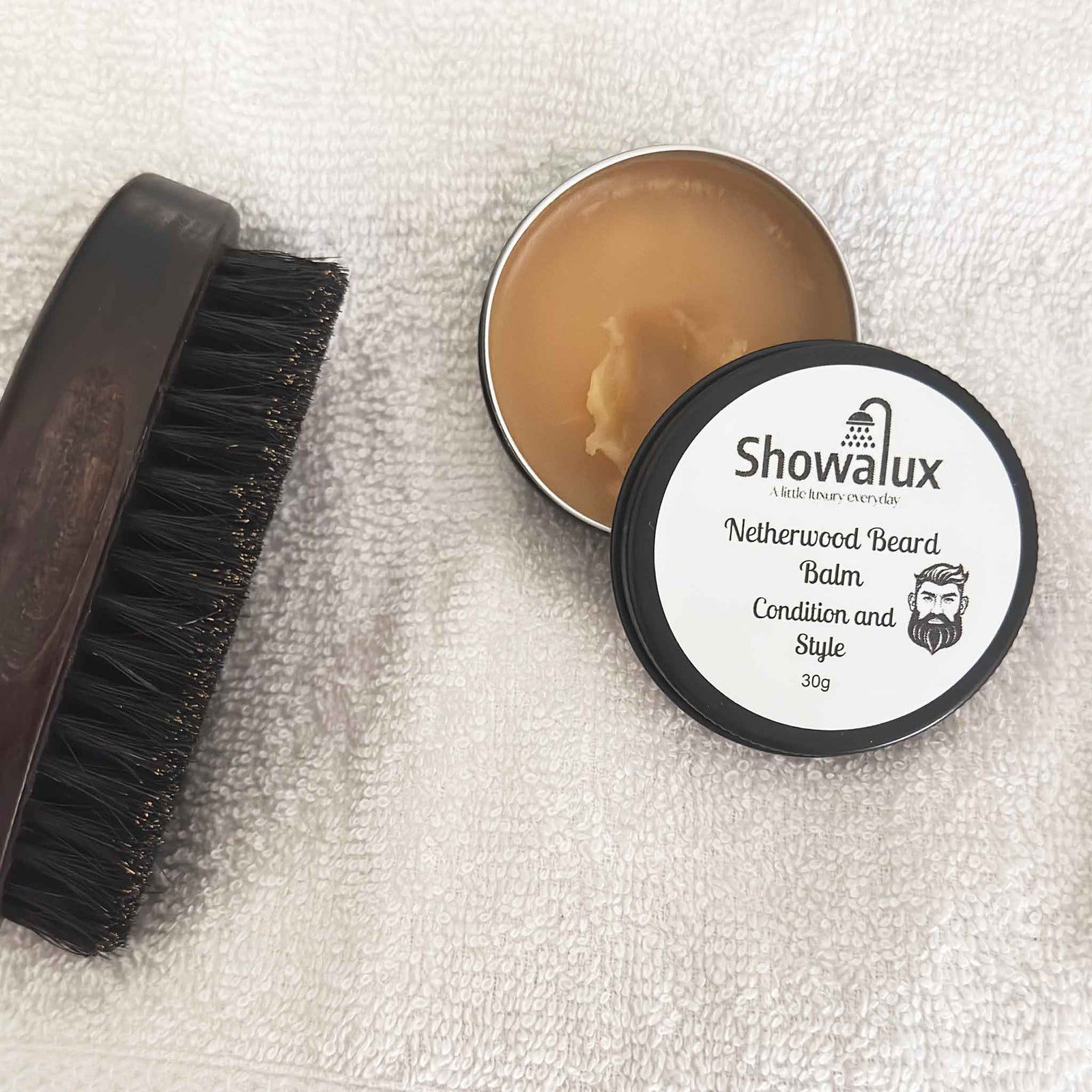 Showalux Netherwood Beard Balm with a brush on a textured white surface