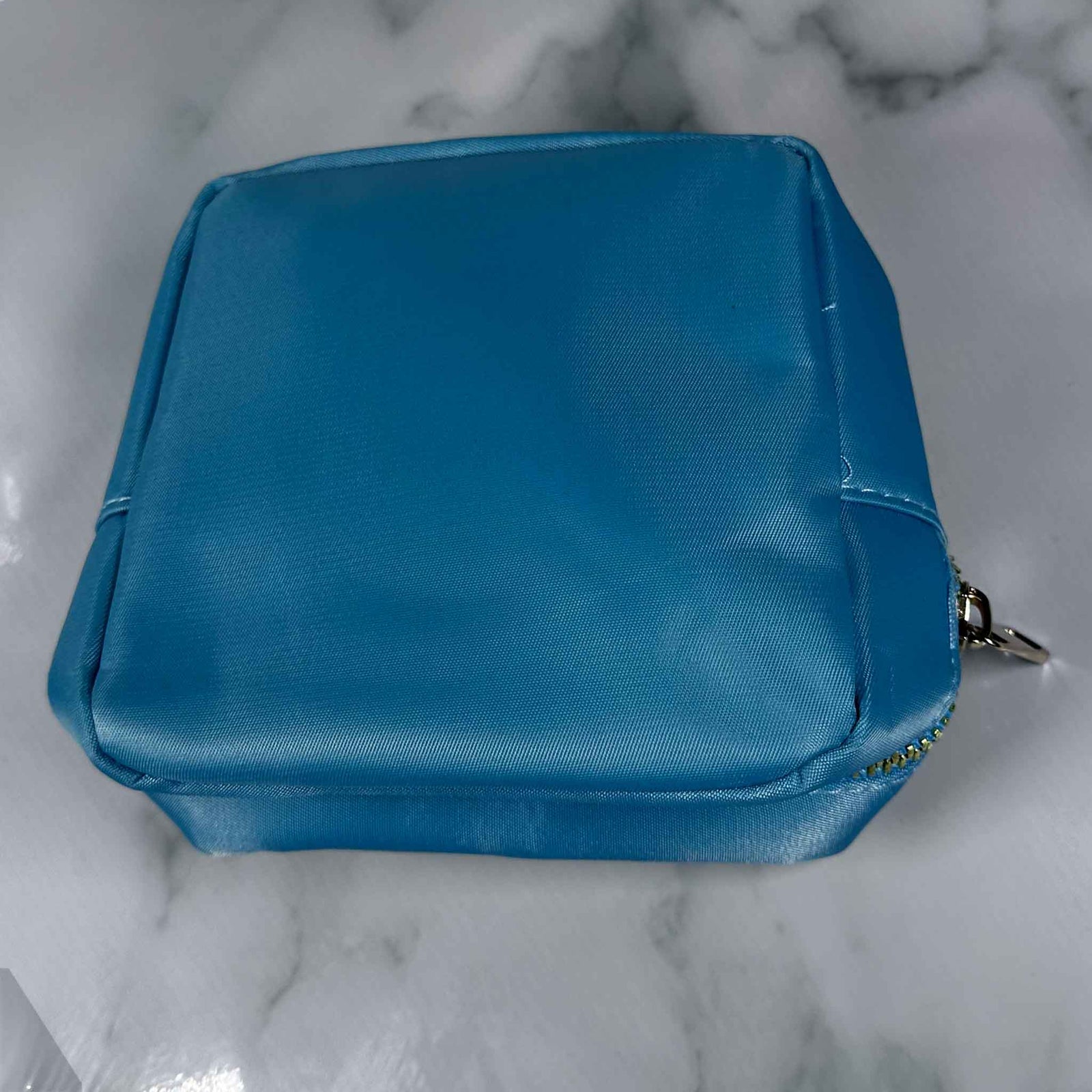 Blue Showalux personal bag with a zipper on a marble surface