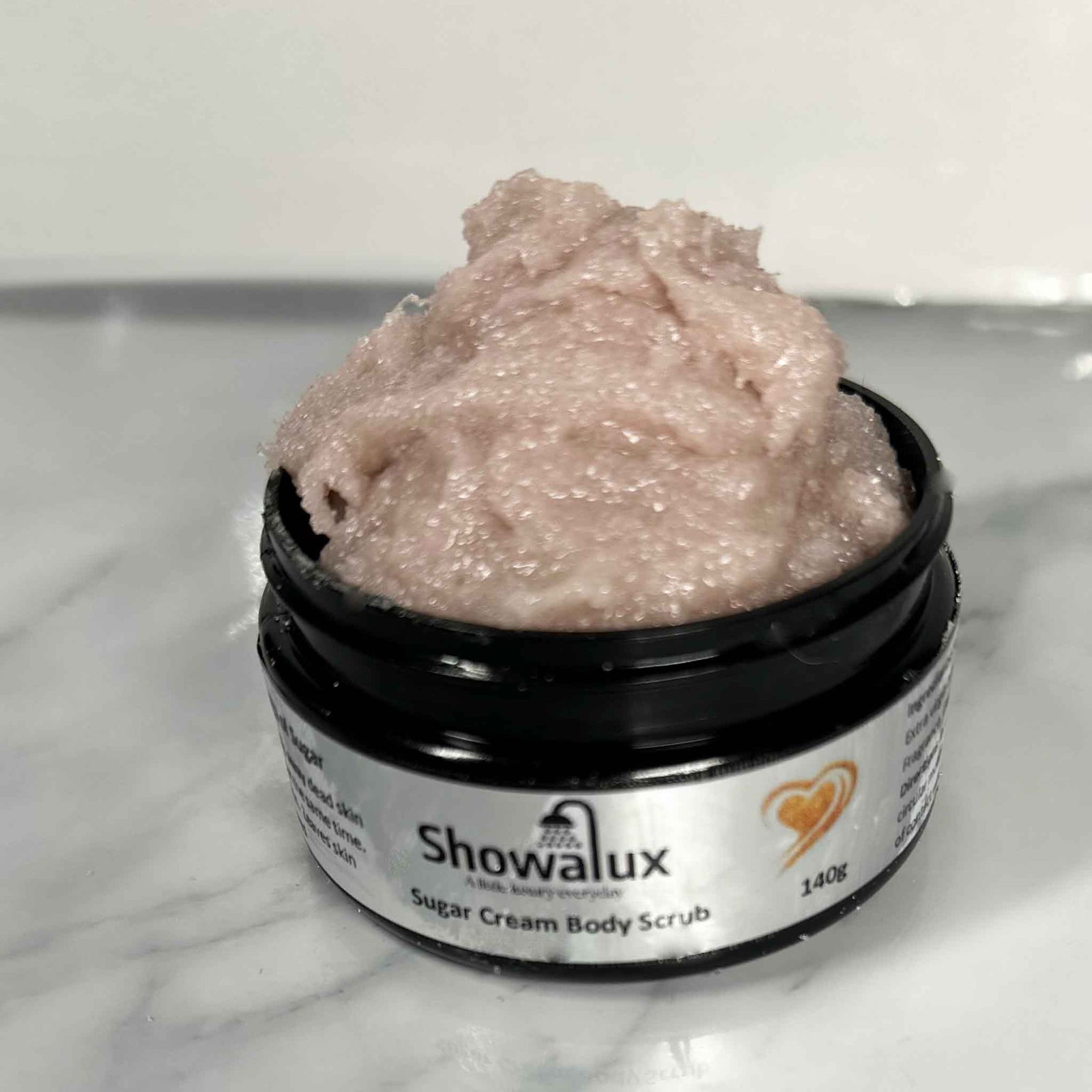 Showalux sugar cream body scrub in a jar on a marble surface