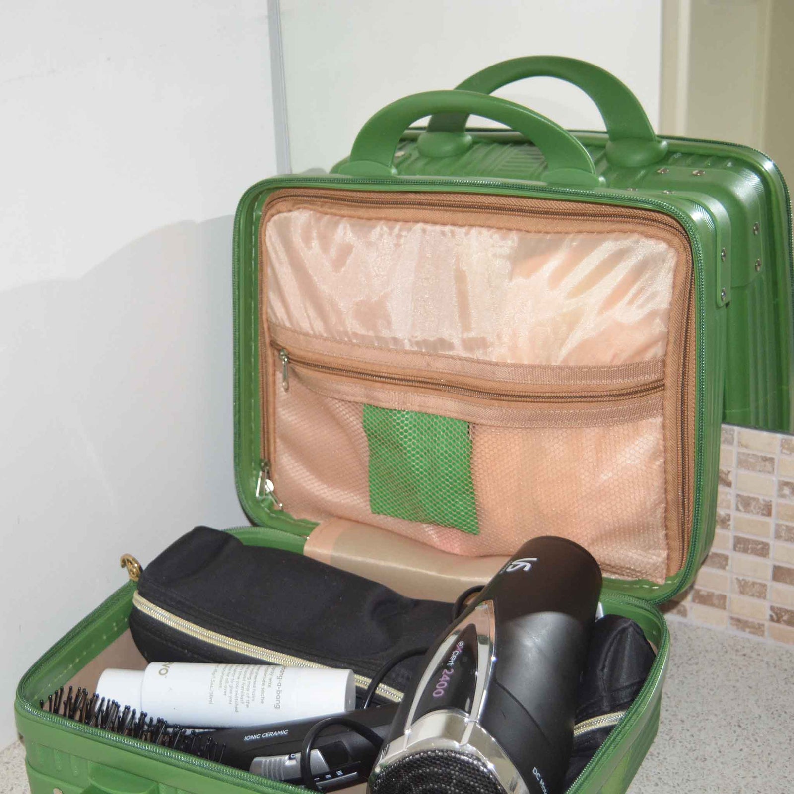 Green Suitcase style bag on a bench, open showing hair equipment