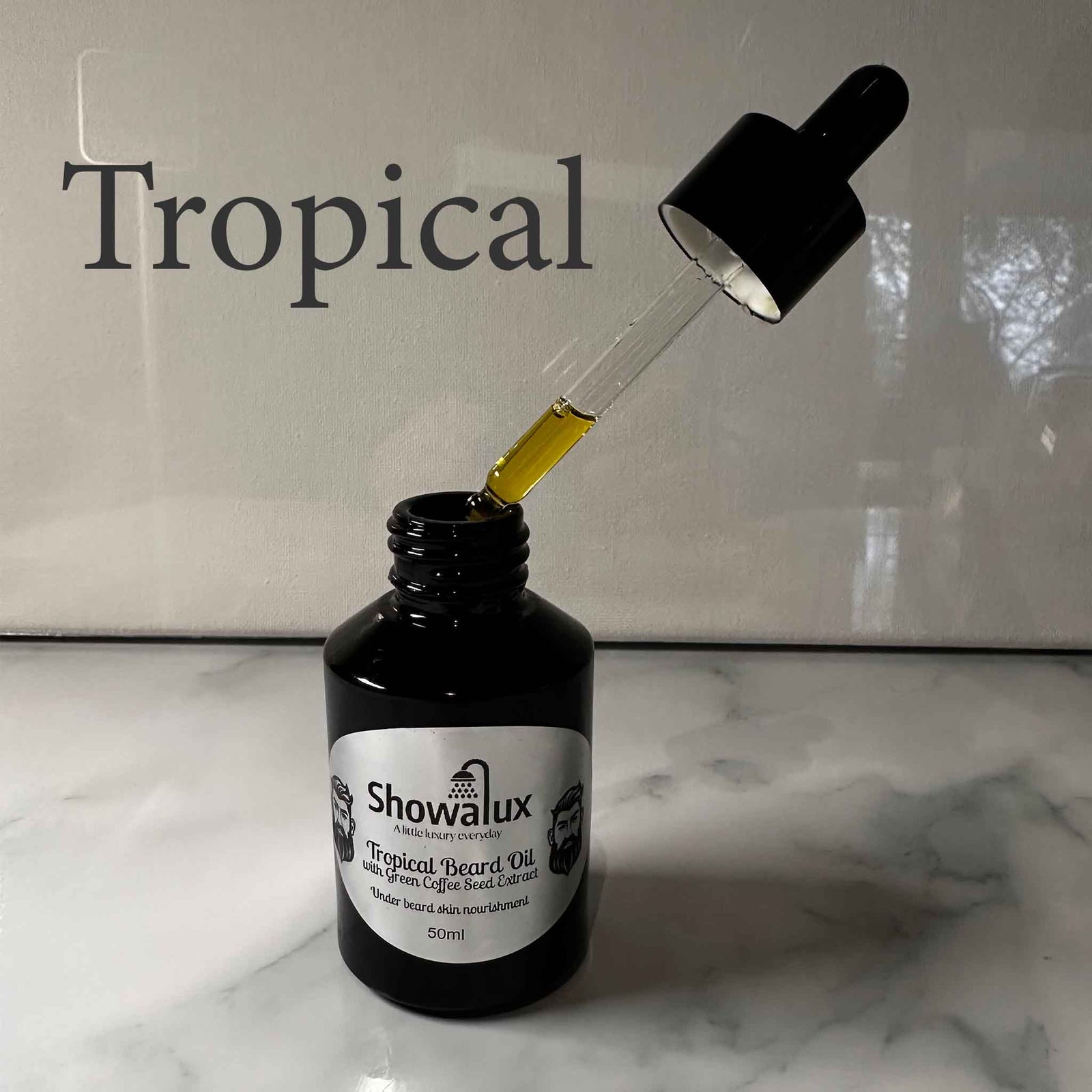 A small bottle of beard oil with a silver label and an eye dropper, dripping oil into the bottle fragrance is Tropical