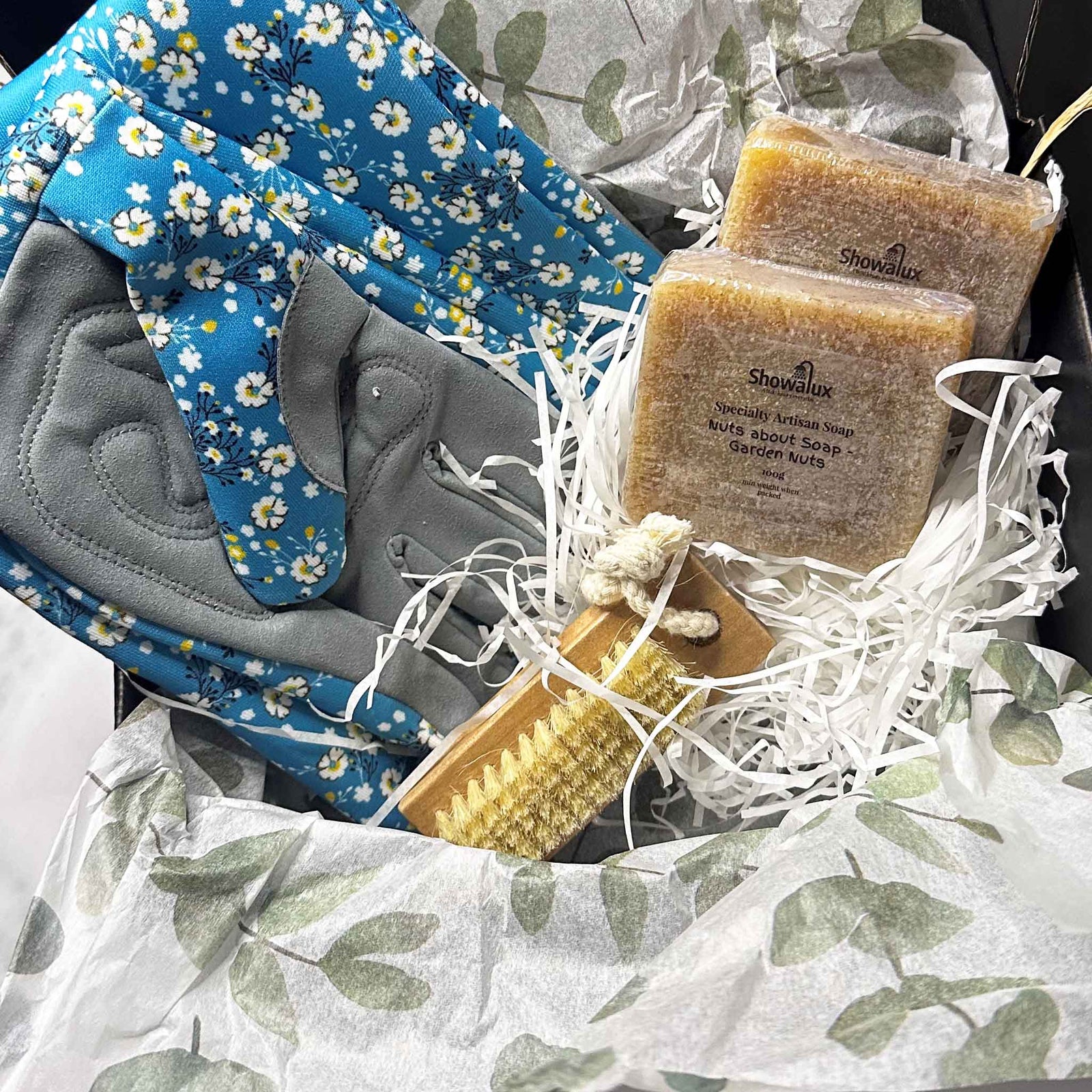 Gift basket with gloves with blue floral fabric, and Showalux soap bars on a white background.