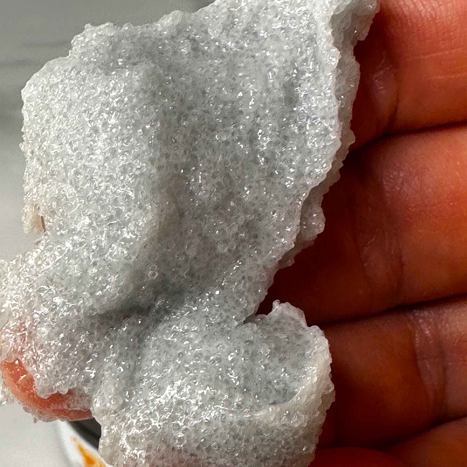 Close-up of a hand holding a piece Cambrian blue sugar scrub.