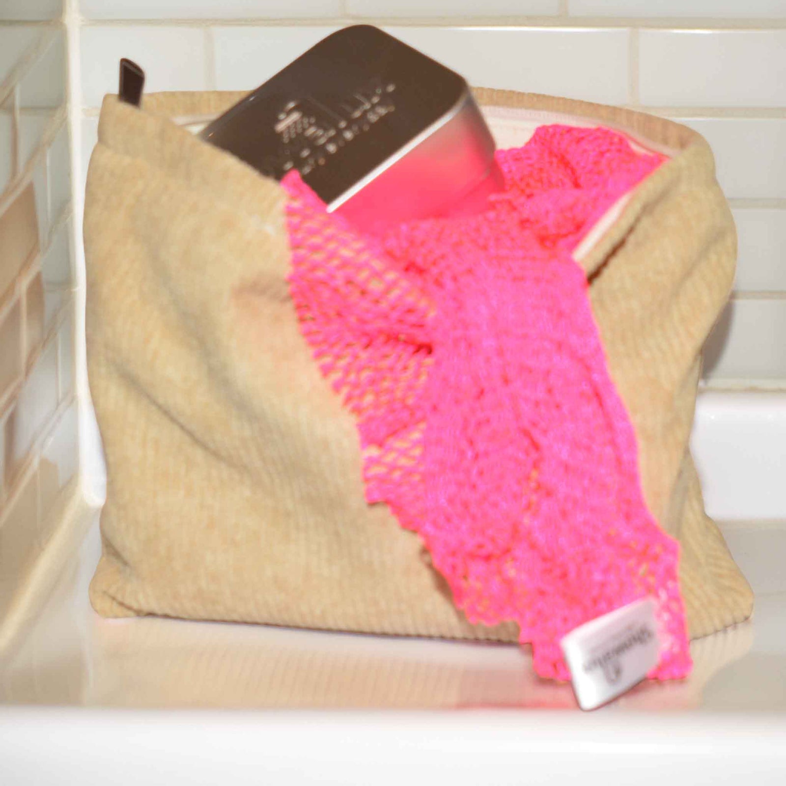 Camel coloured corduroy cosmetic bag with a soap tin and african net sponge showing from on top on a white background