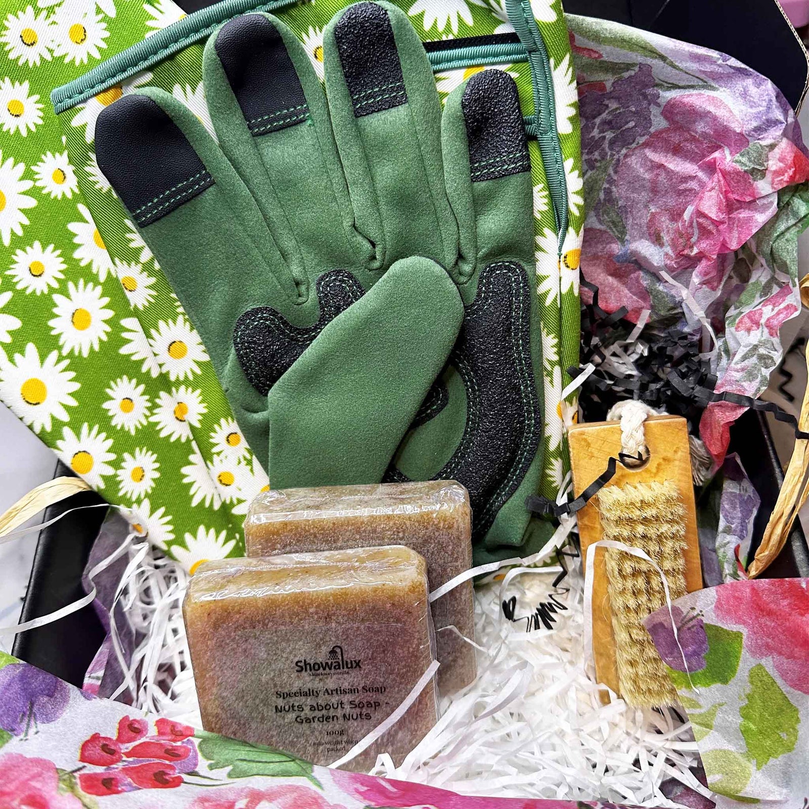 Gardening tools including gloves, a brush, and soap in a decorative box with floral patterns.