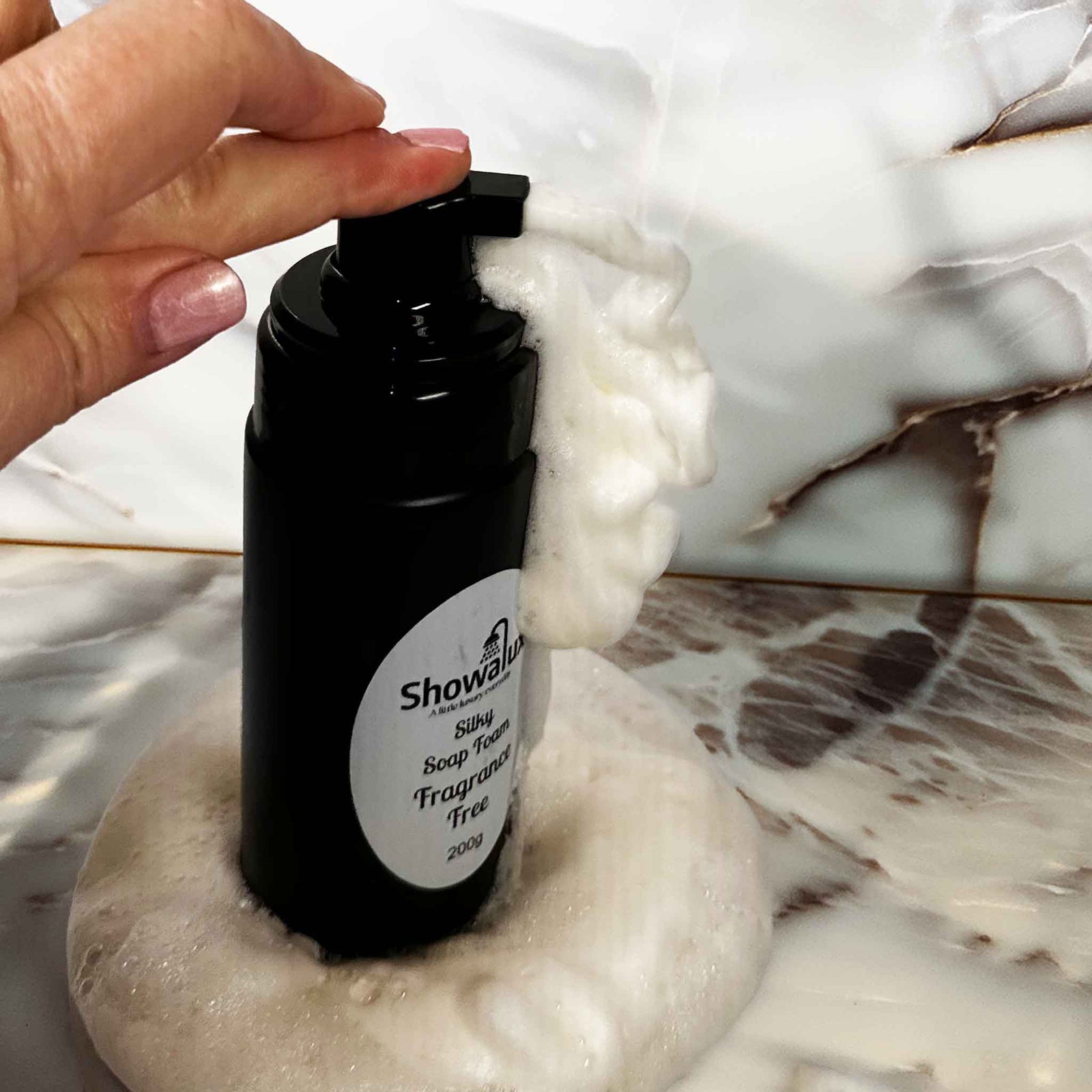 Black bottle of Showalux liquid soap with a hand applying soap on a marble surface
