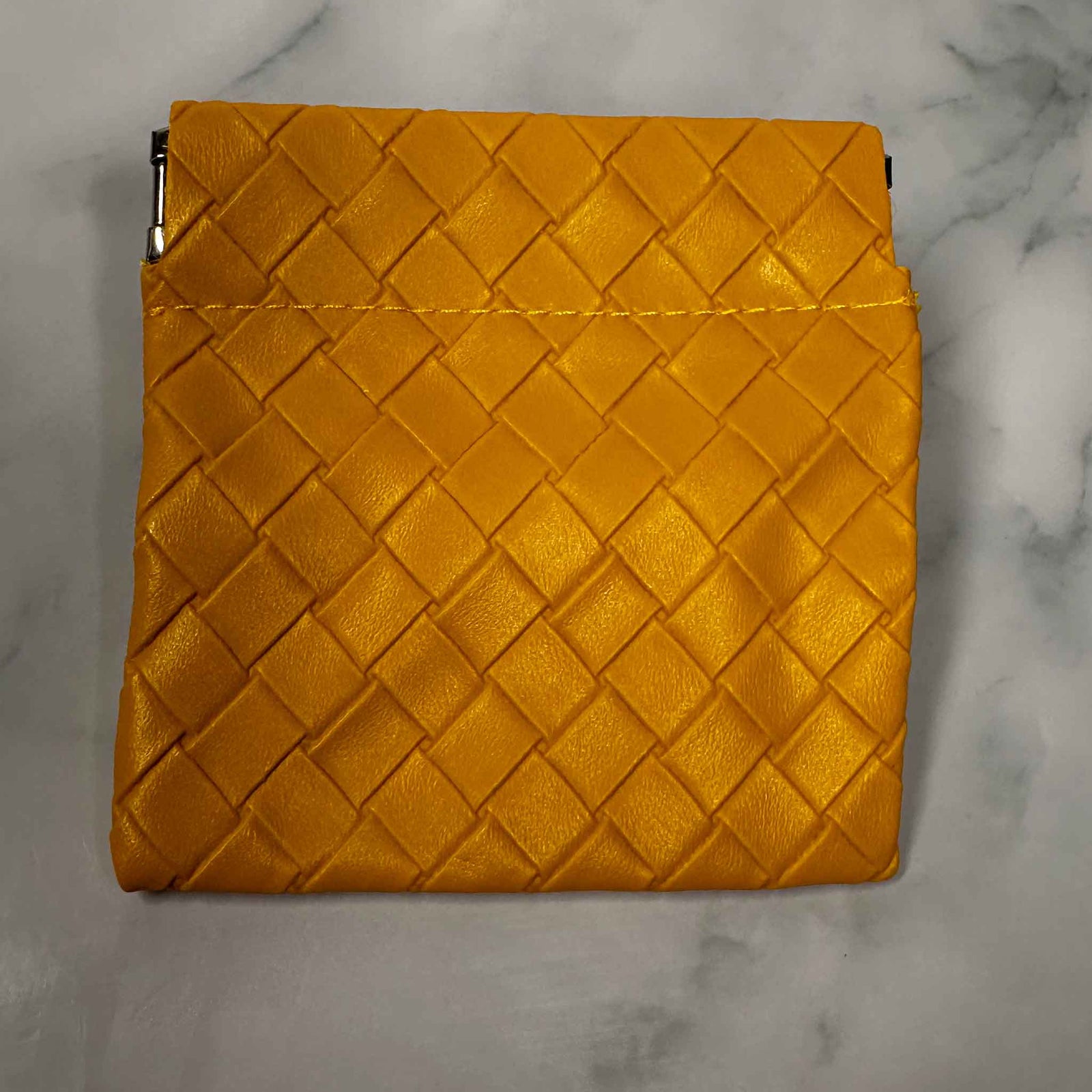 Gold woven personal Showalux bag on a marble surface