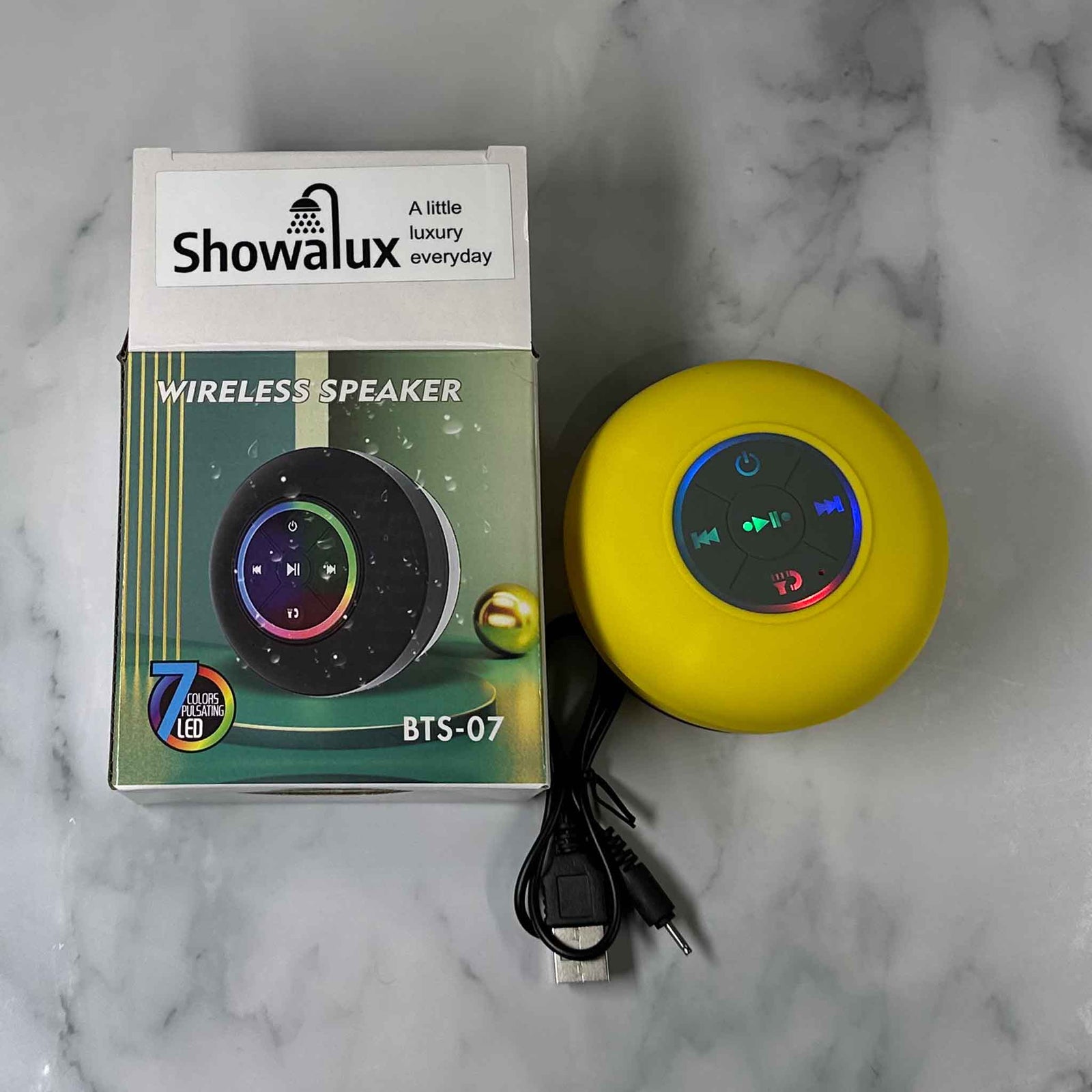 Showalux wireless speaker with packaging and USB cable on a marble surface