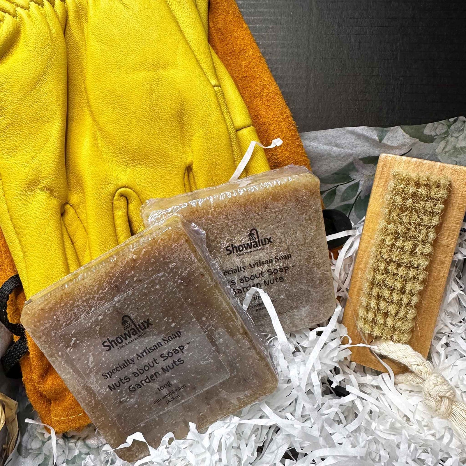 Showalux soap bars with a brush and yellow gloves on white shredded paper