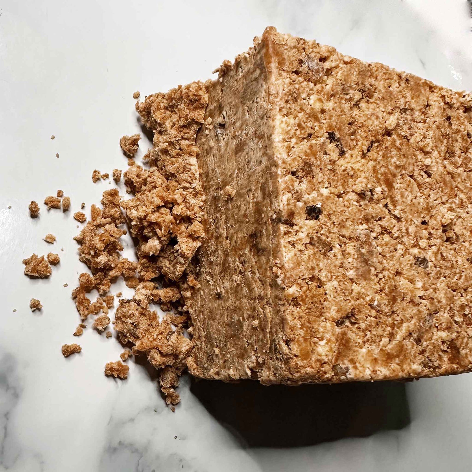 Slice of crumbly black soap on a marble surface