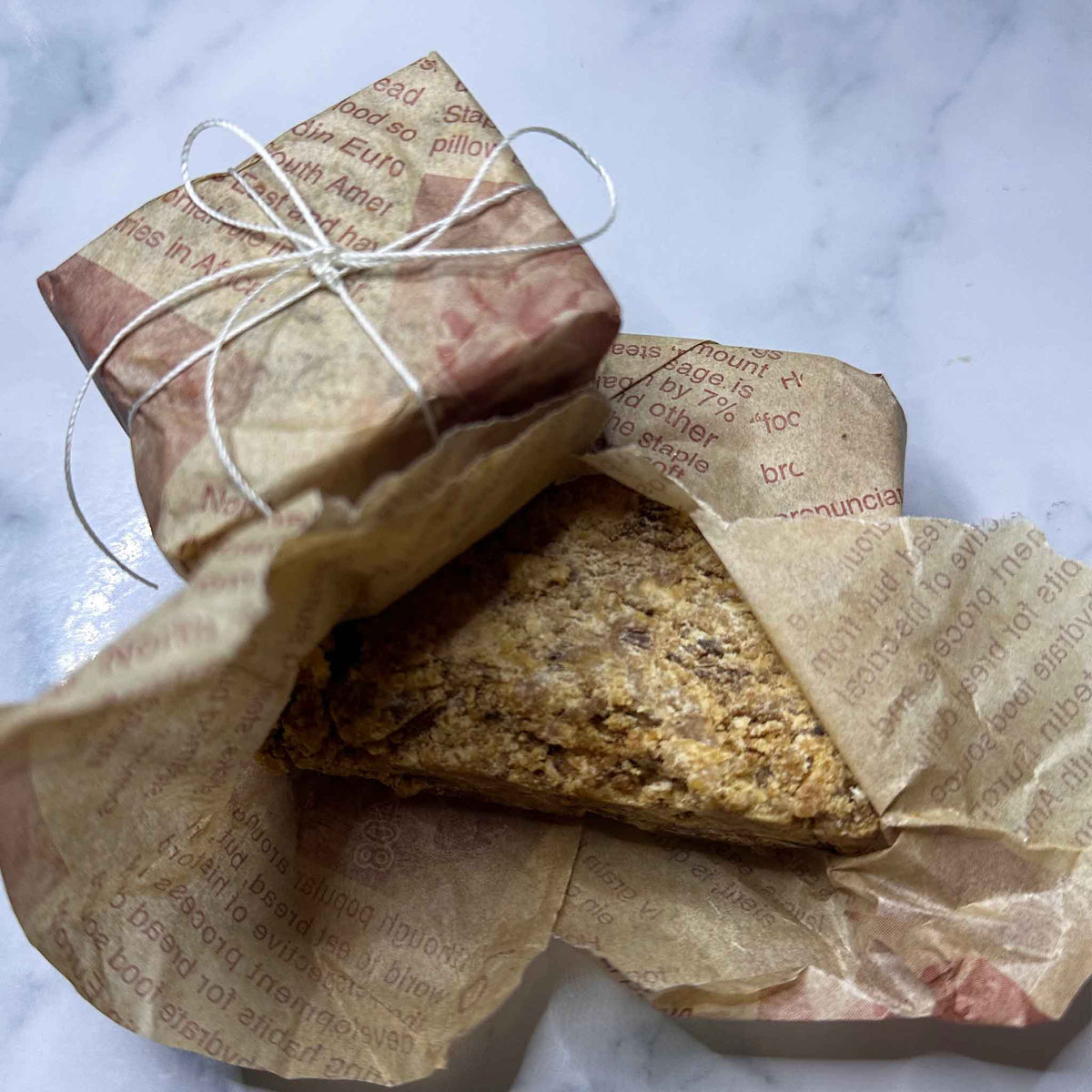 Black soap, wrapped in brown paper with text on a marble surface.