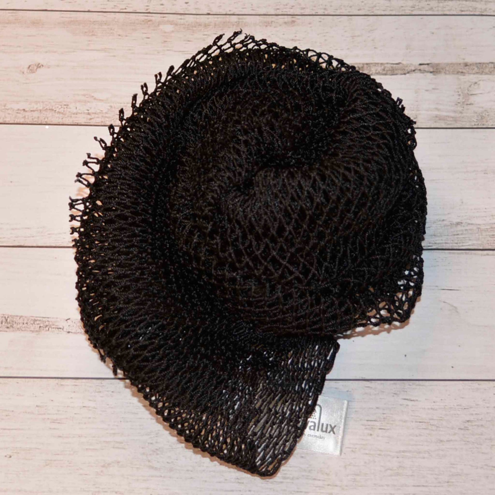 A coil of African Net Sponge coloured Black on a white background