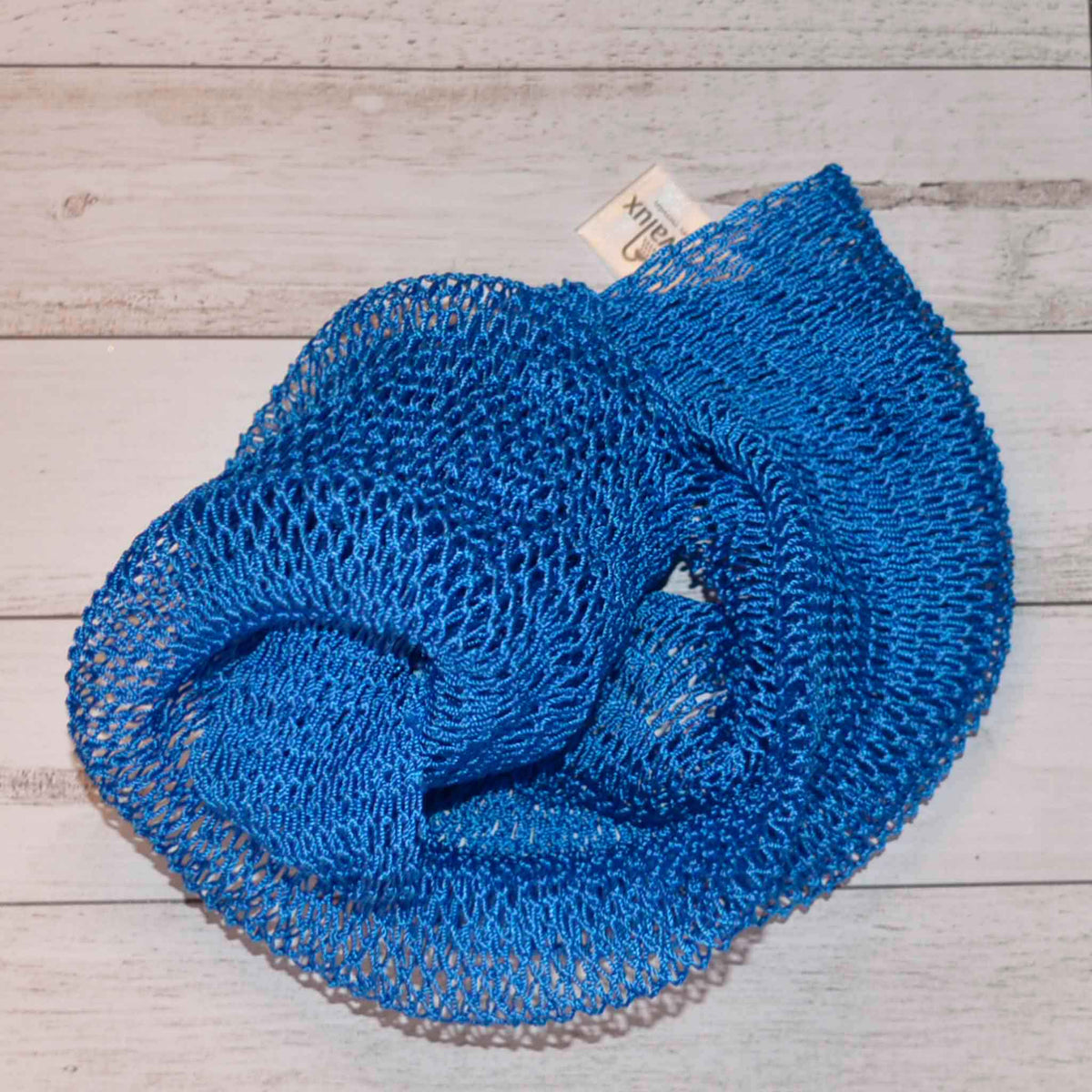 A coil of African Net Sponge coloured bright blue on a white background