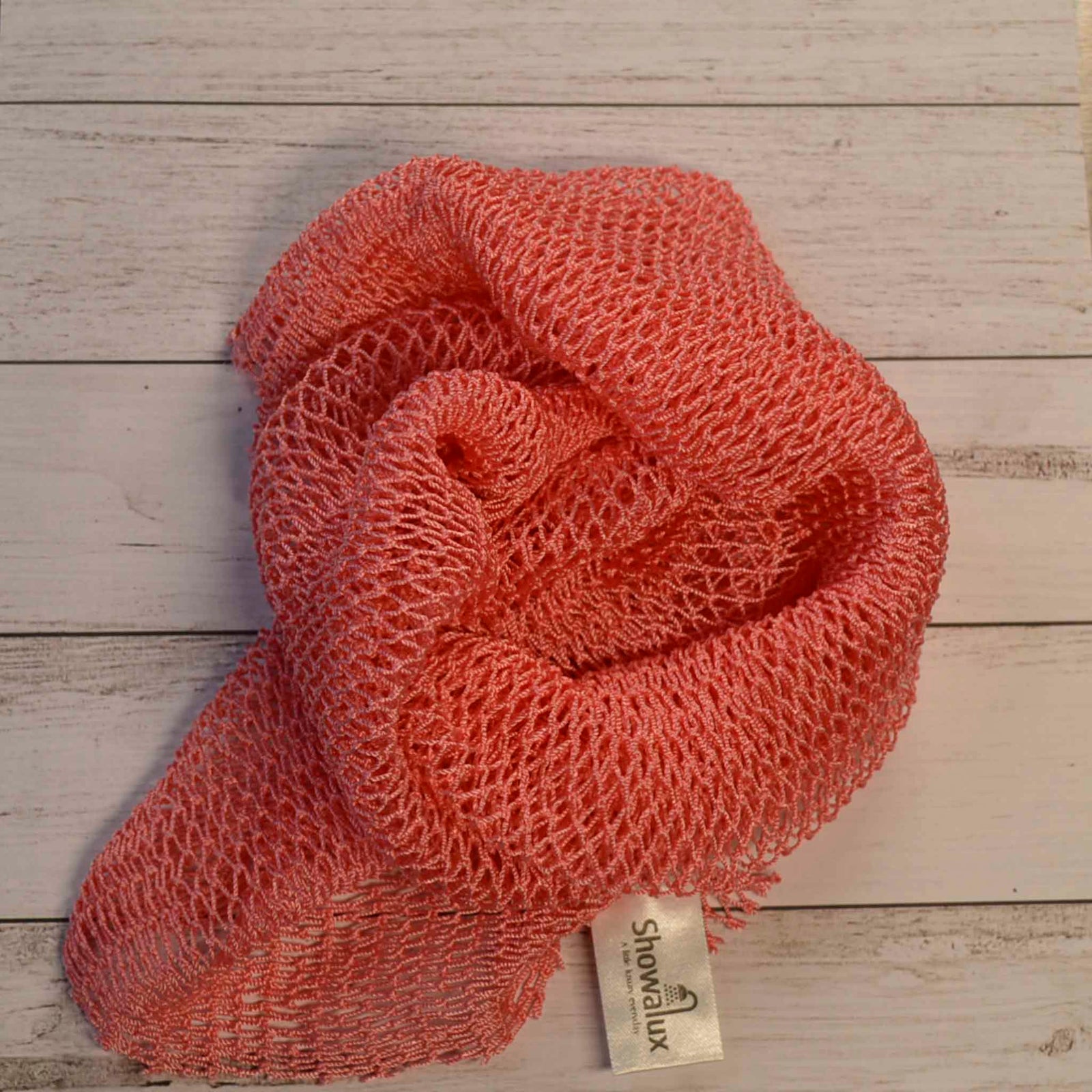 A coil of African Net Sponge coloured Salmon Pink on a white background