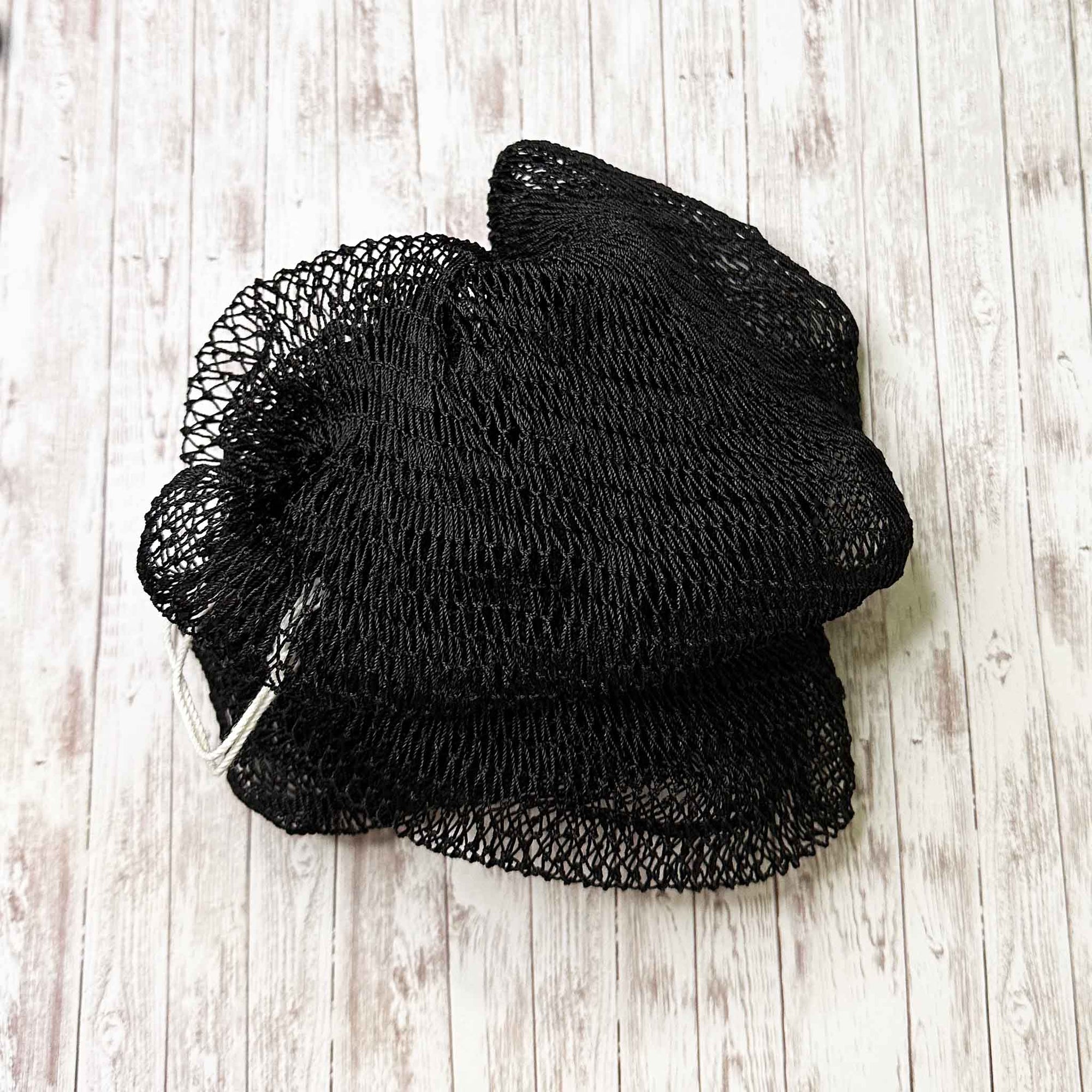 A coil of African Net Sponge coloured Black on a white background