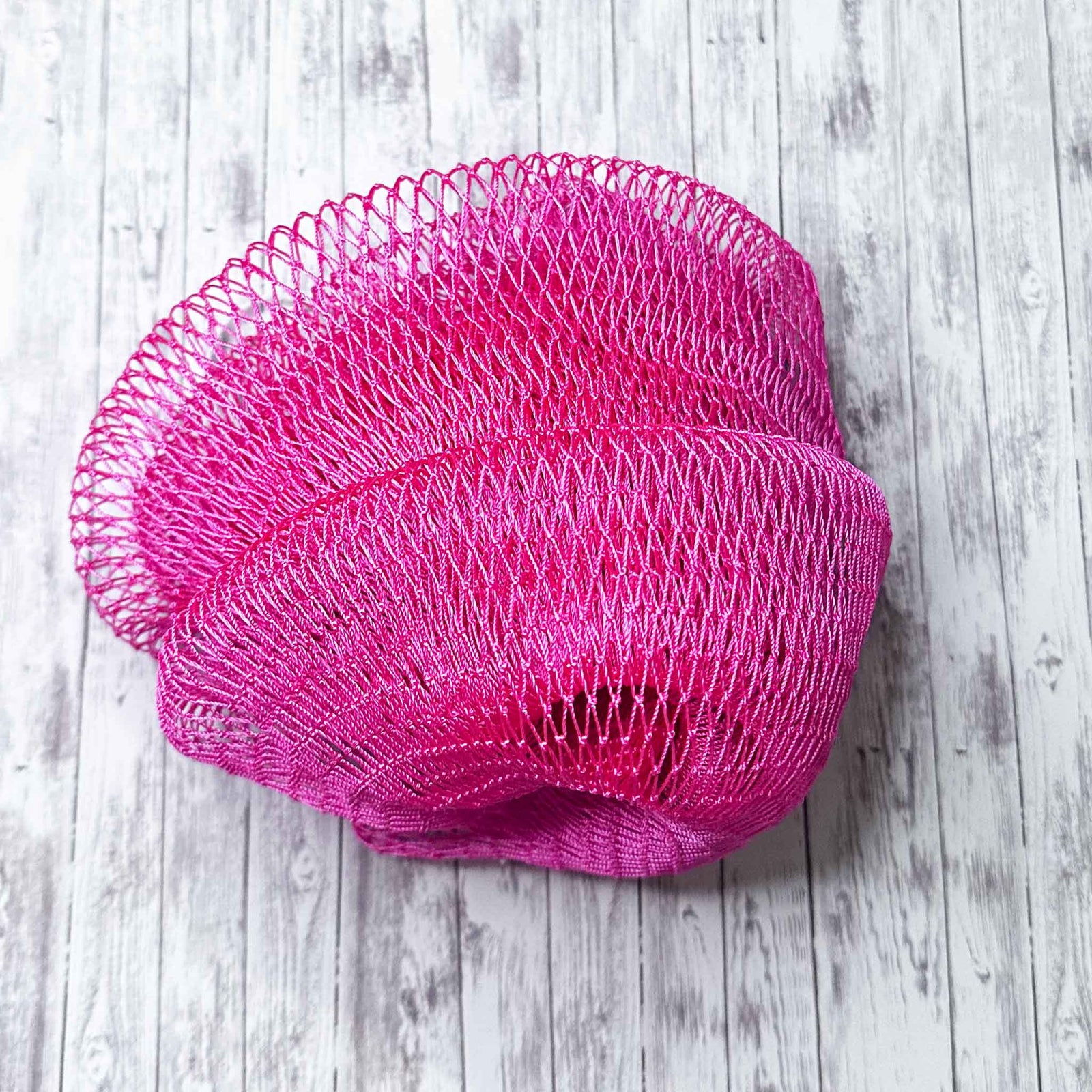 A coil of African Net Sponge coloured Deep Pink on a white background