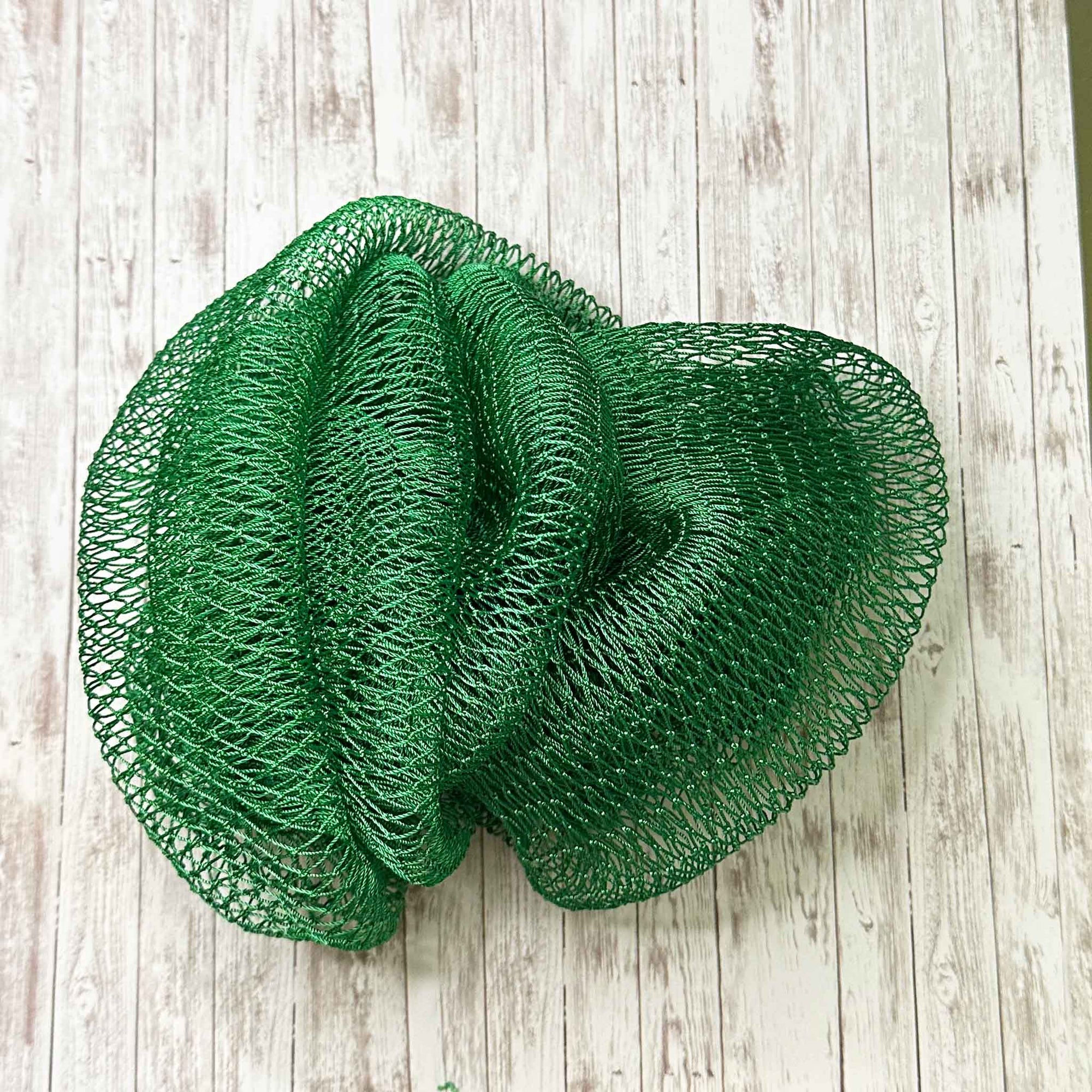 A coil of African Net Sponge coloured Emerald Green on a white background