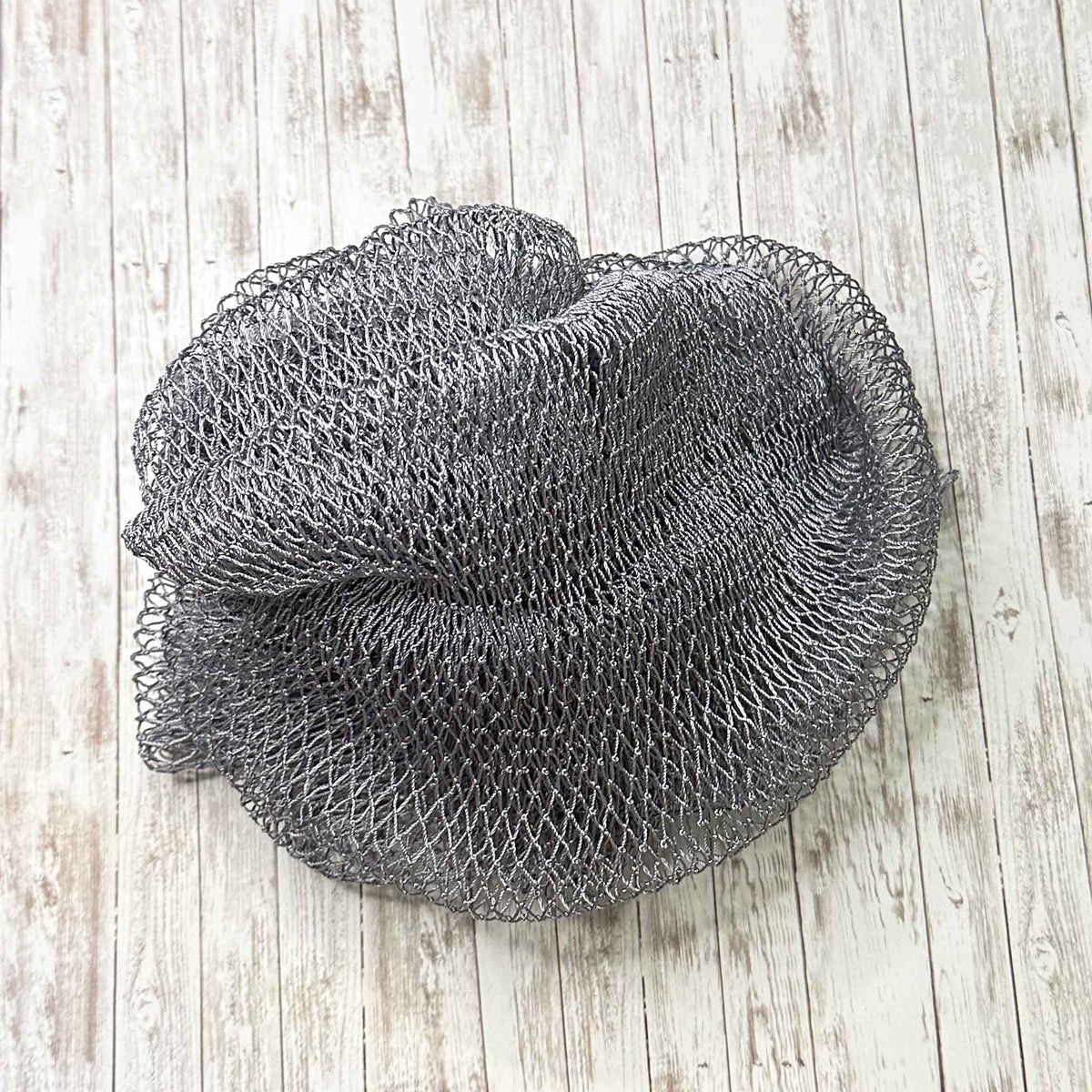 A coil of African Net Sponge coloured Gray on a white background