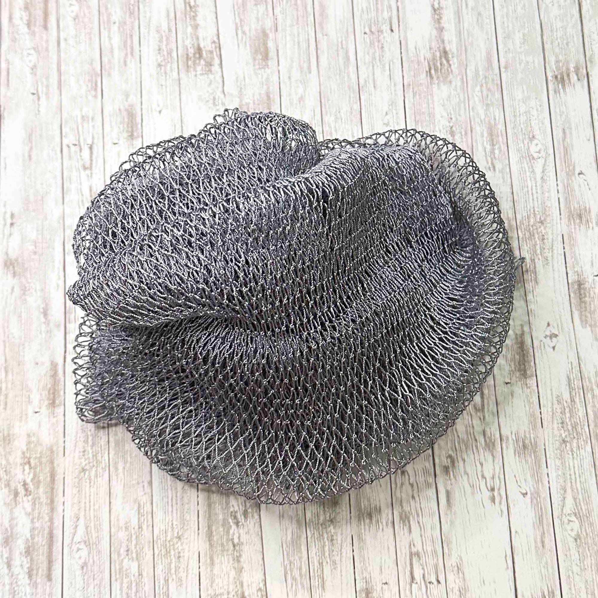 A coil of African Net Sponge coloured Gray on a white background