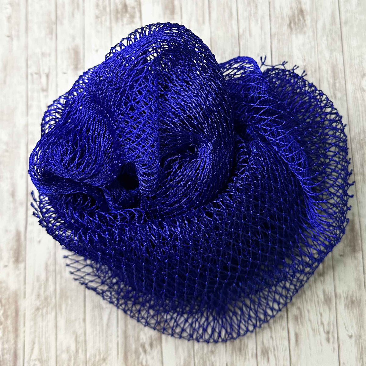 A coil of African Net Sponge coloured Navy on a white background