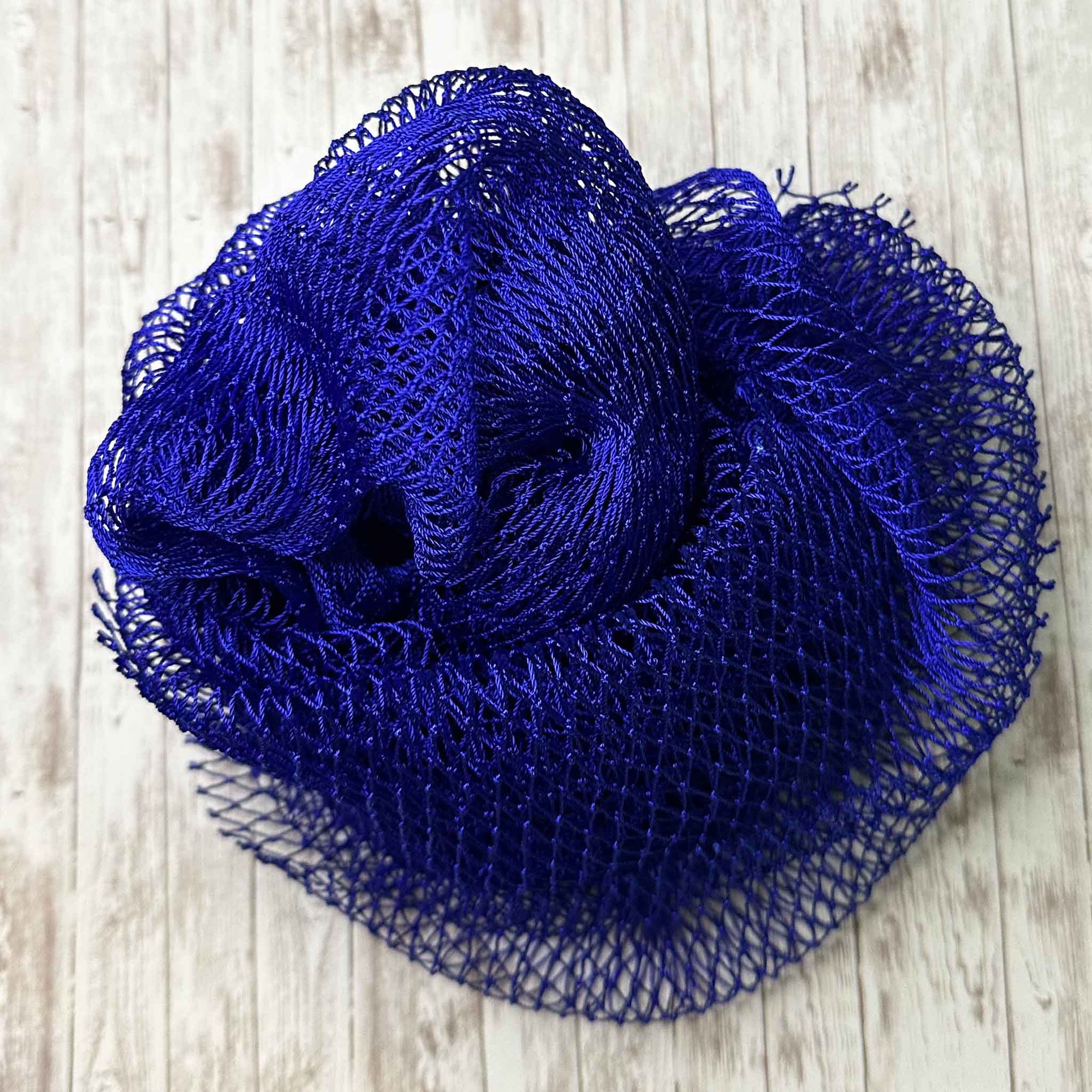 A coil of African Net Sponge coloured Navy on a white background
