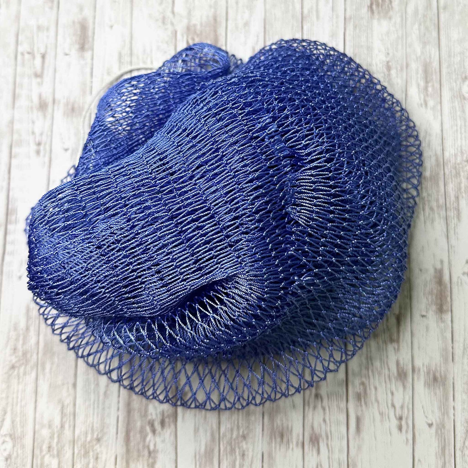 A coil of African Net Sponge coloured Periwinkle on a white background