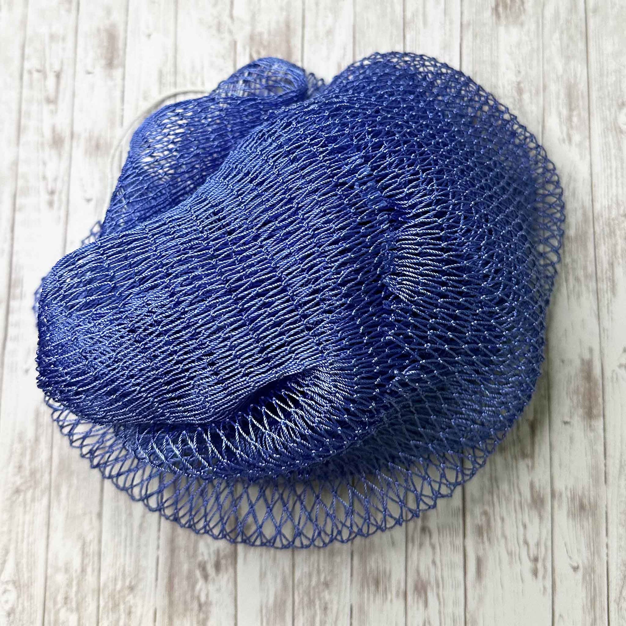 A coil of African Net Sponge coloured Periwinkle on a white background