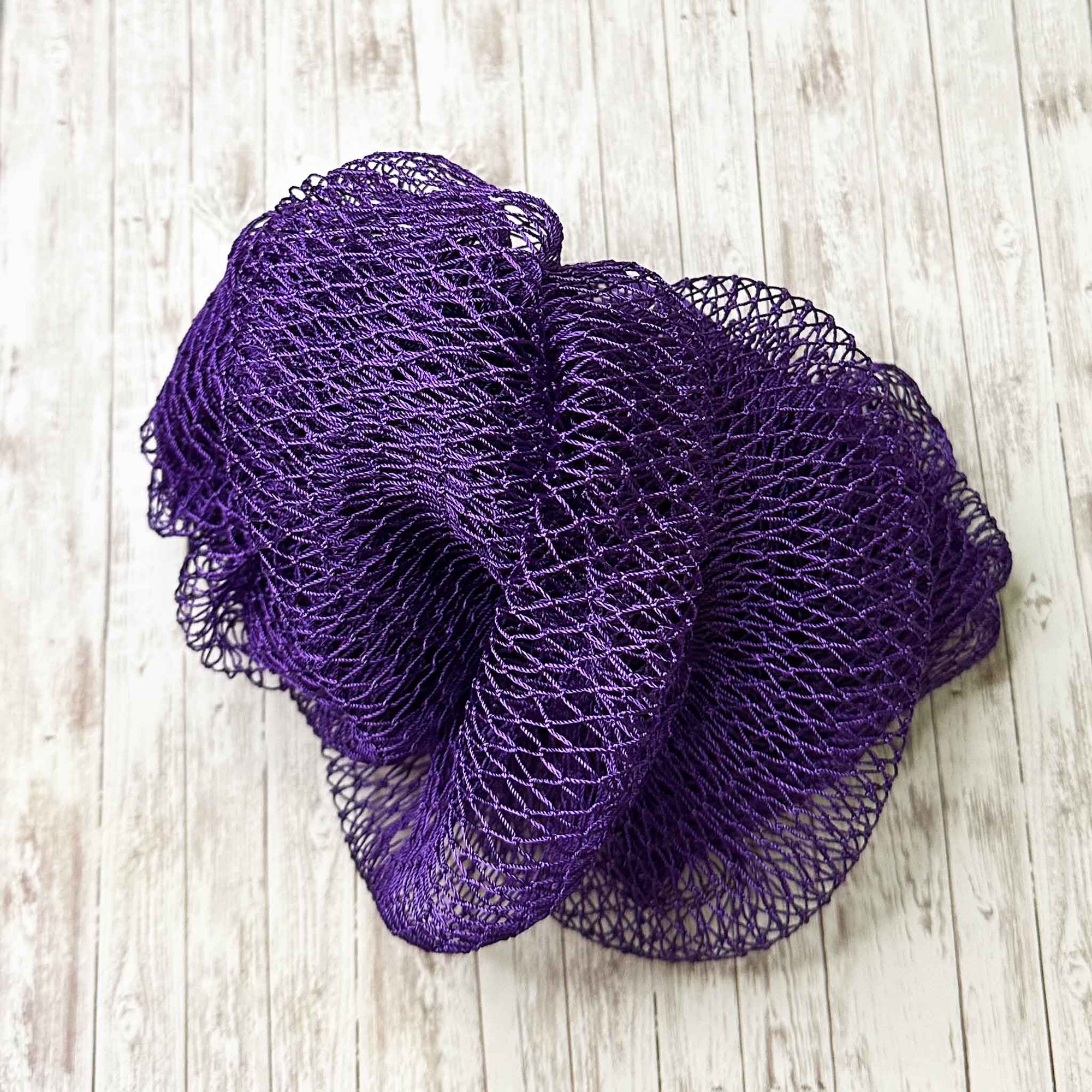A coil of African Net Sponge coloured Purple on a white background