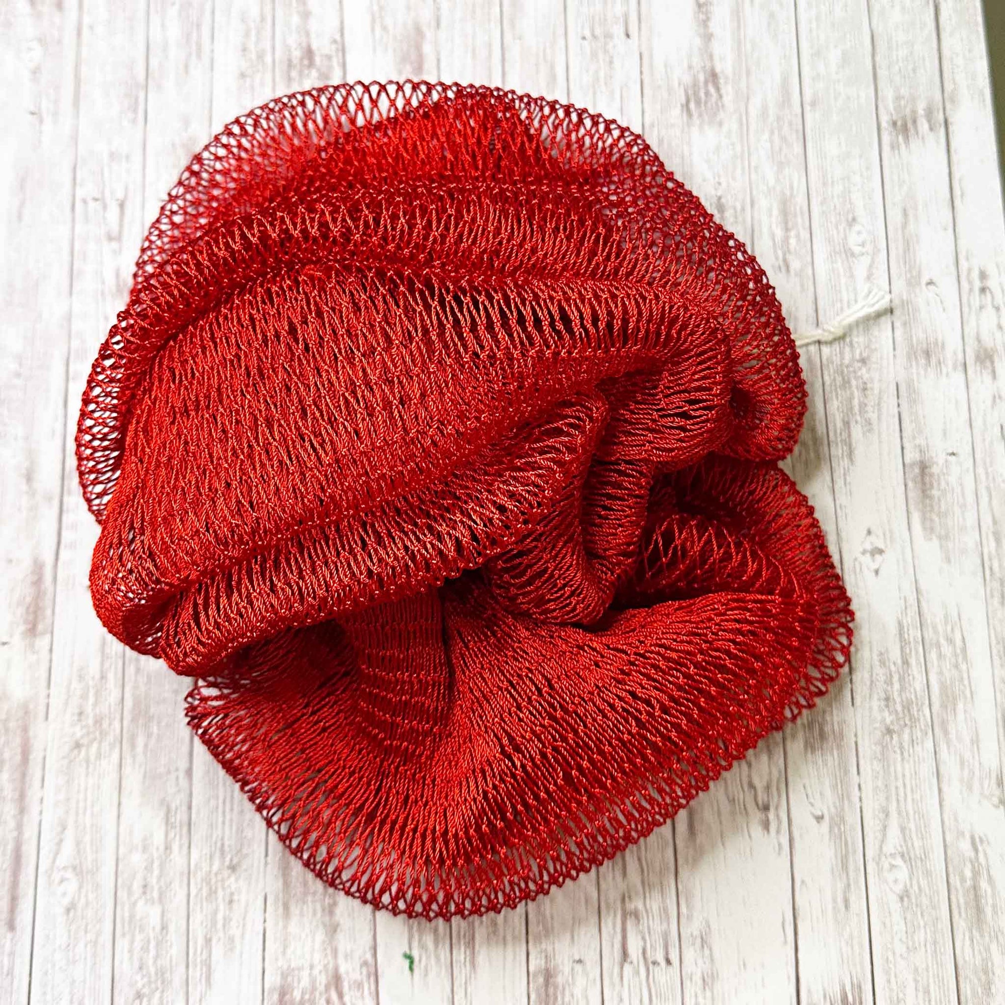 A coil of African Net Sponge coloured Red on a white background