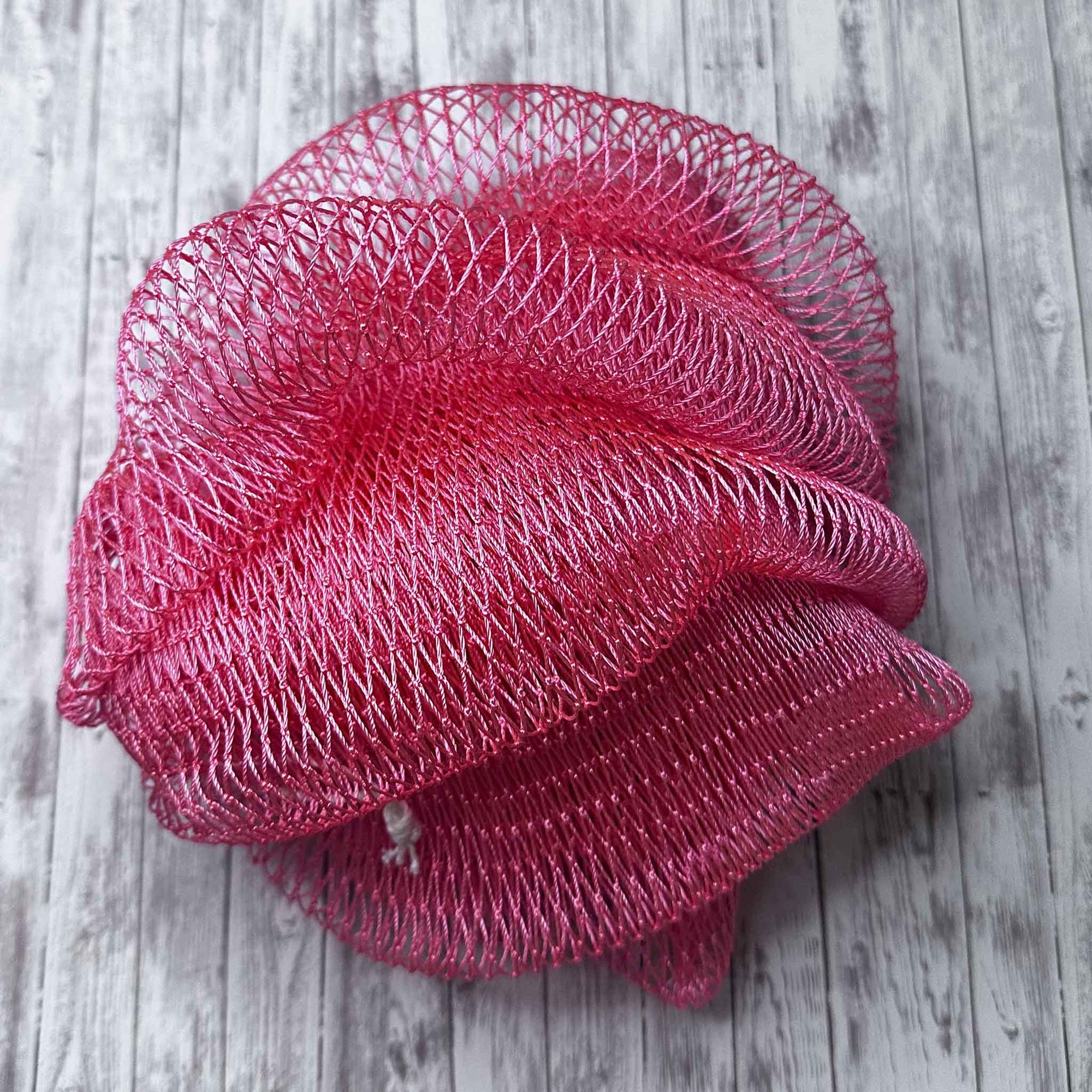 A coil of African Net Sponge coloured Salmon on a white background