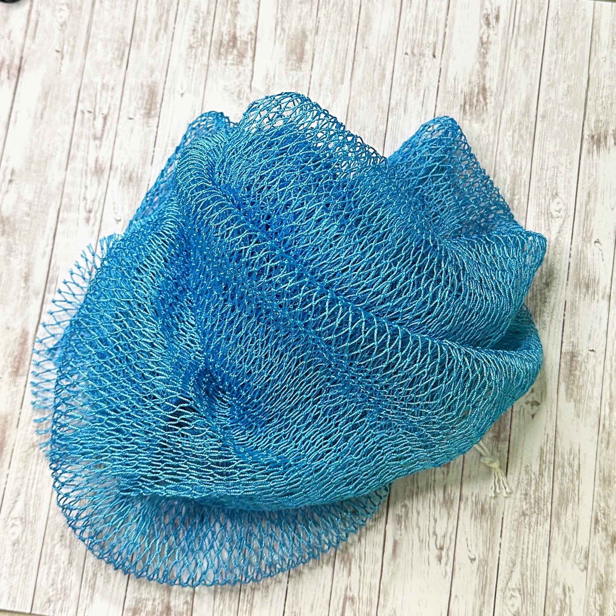 A coil of African Net Sponge coloured light blue on a white background