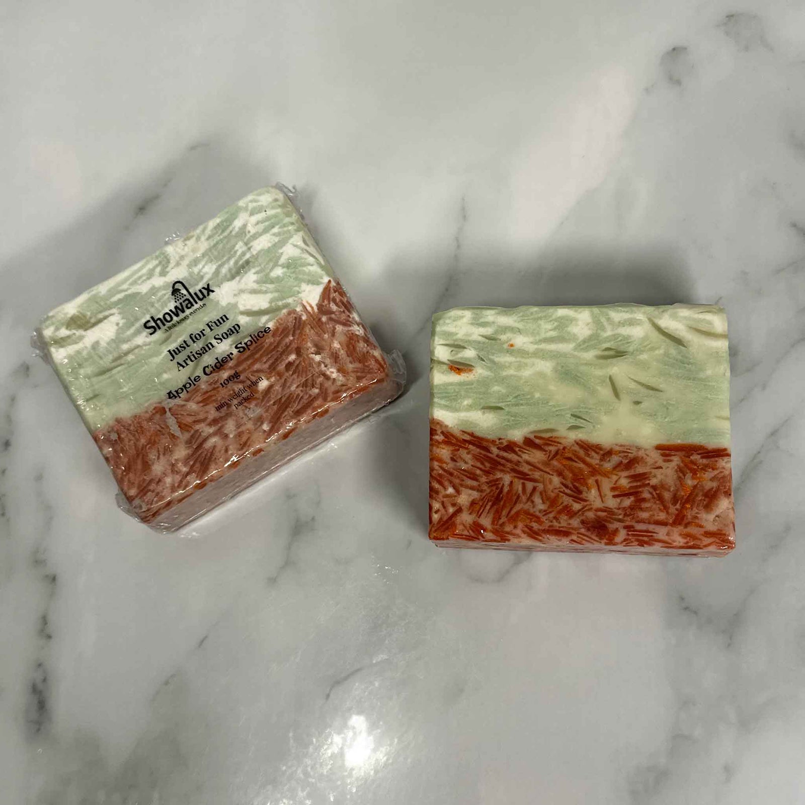 A square cake of soap half red speckled and half green speckled on a marble background