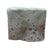 A square cake of soap half red speckled and half green speckled on a marble background