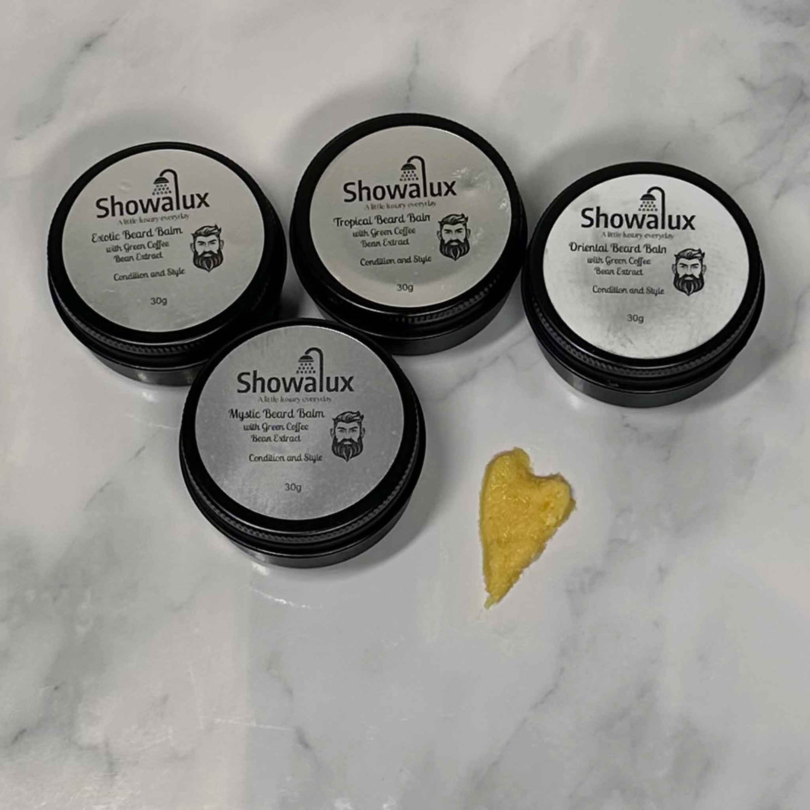 Four Showalux beard balm containers on a marble surface with a small yellow product between them.
