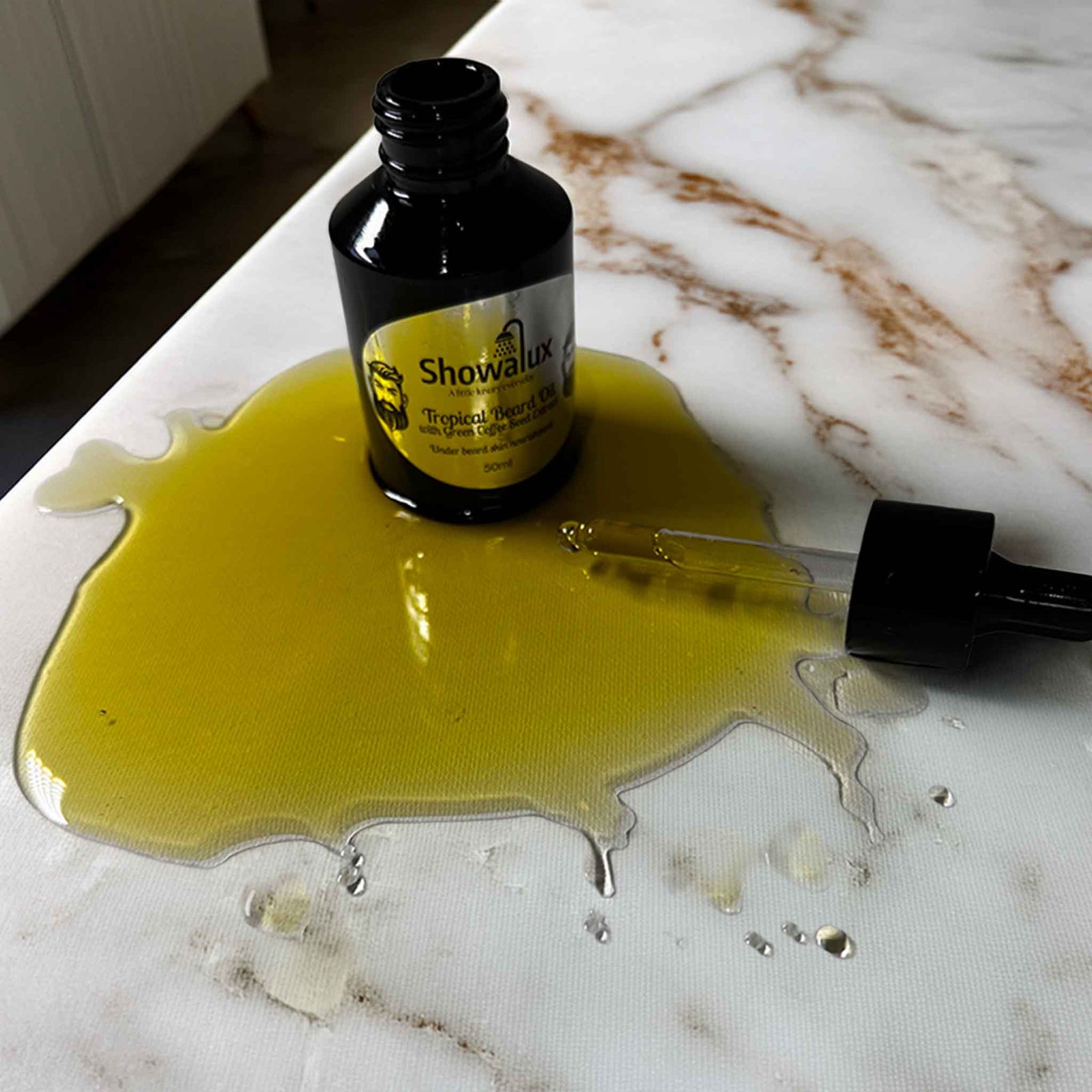 Gold oil spilled on a counter top with a black bottle and eye droppr
