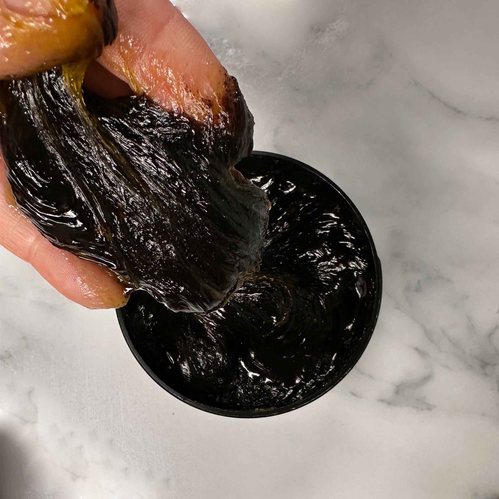 Beldi soap paste on fingers over a jar