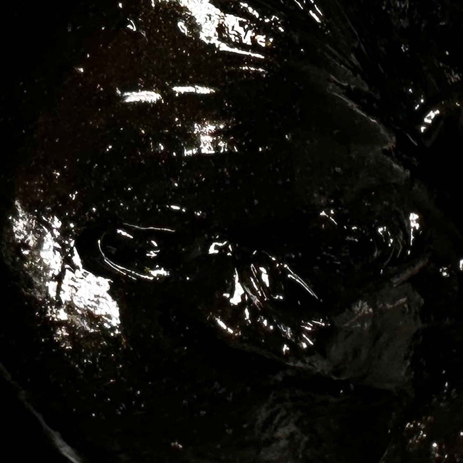 Close-up of shiny black cream soap with reflections