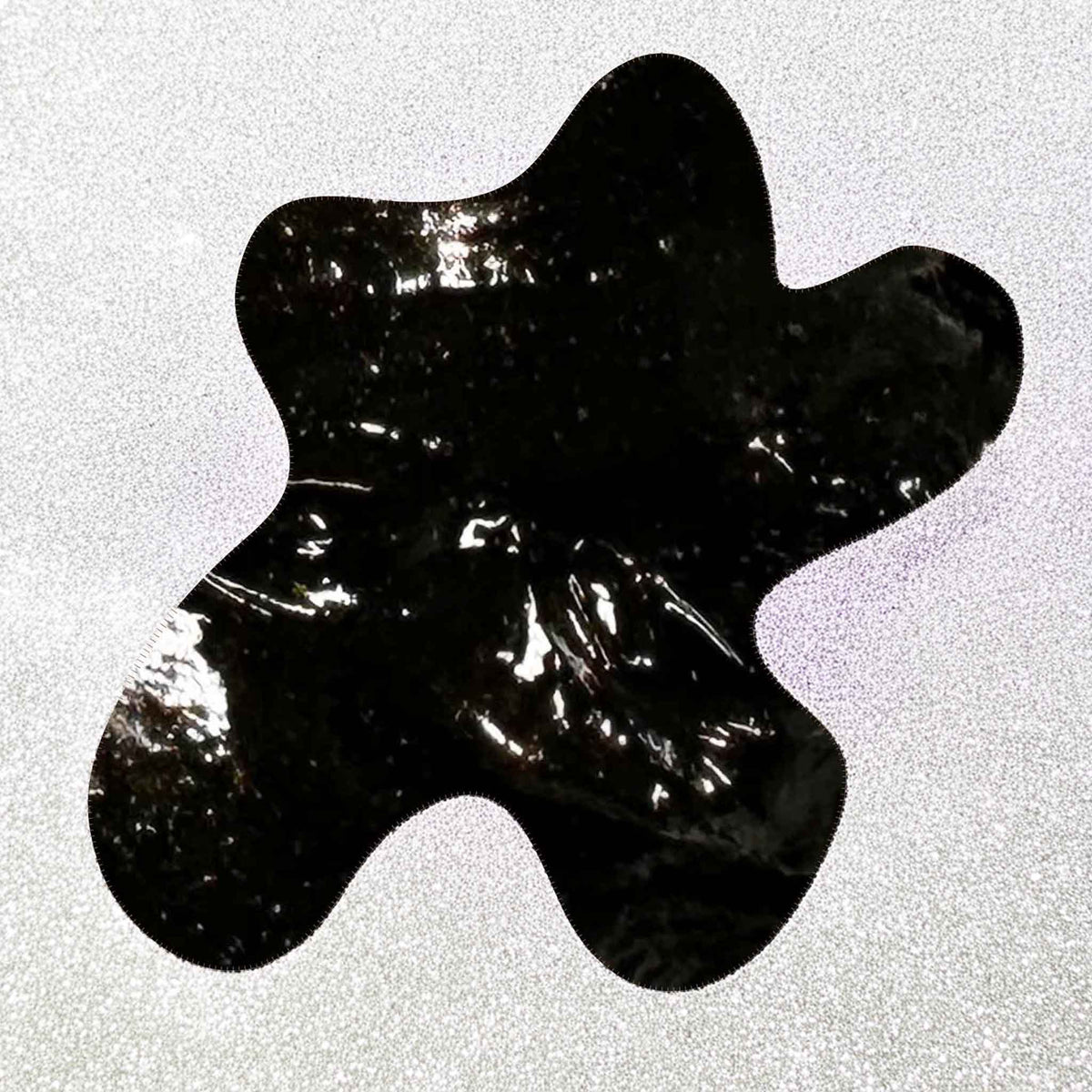 Black cream soap abstract shape on a textured gray background