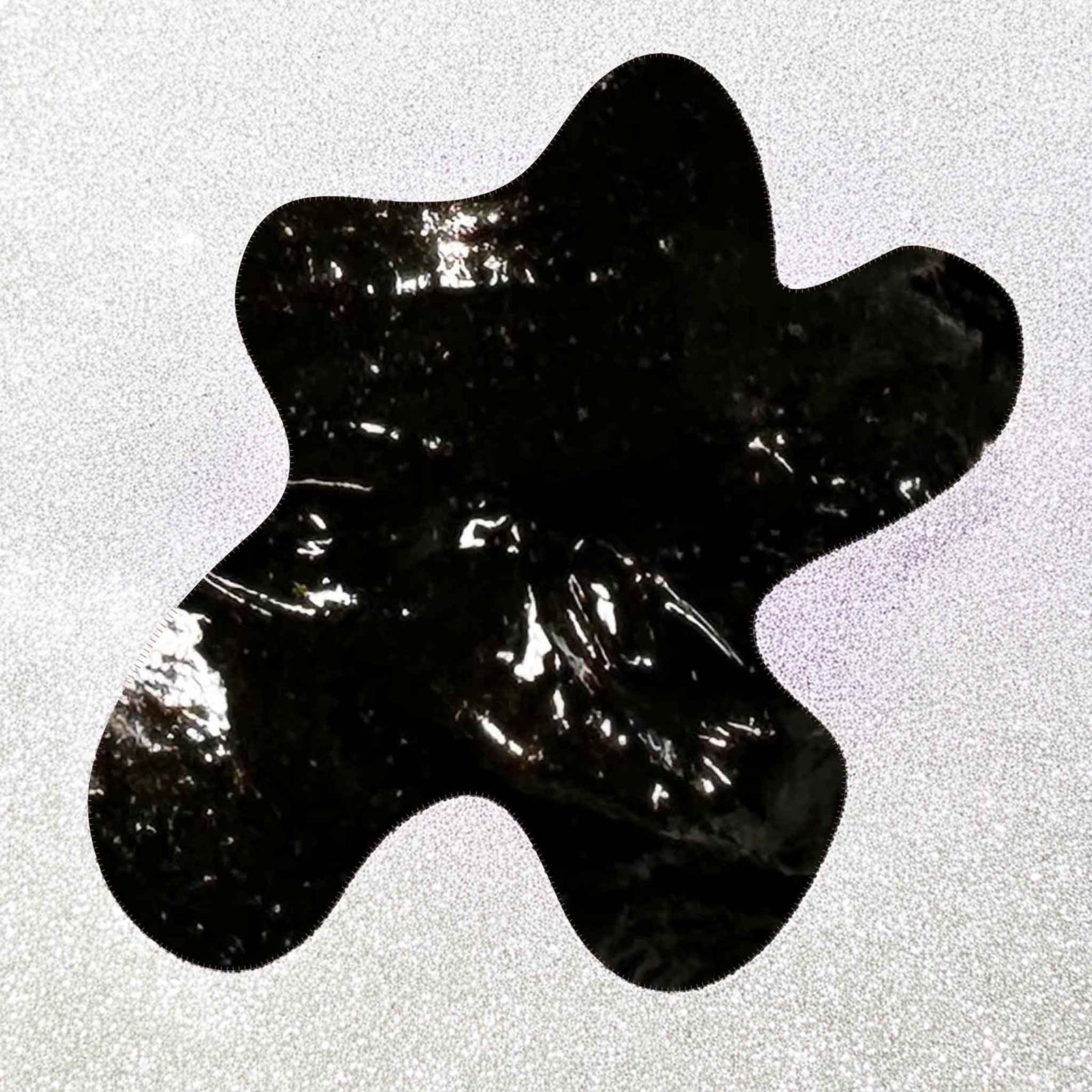 Black cream soap abstract shape on a textured gray background