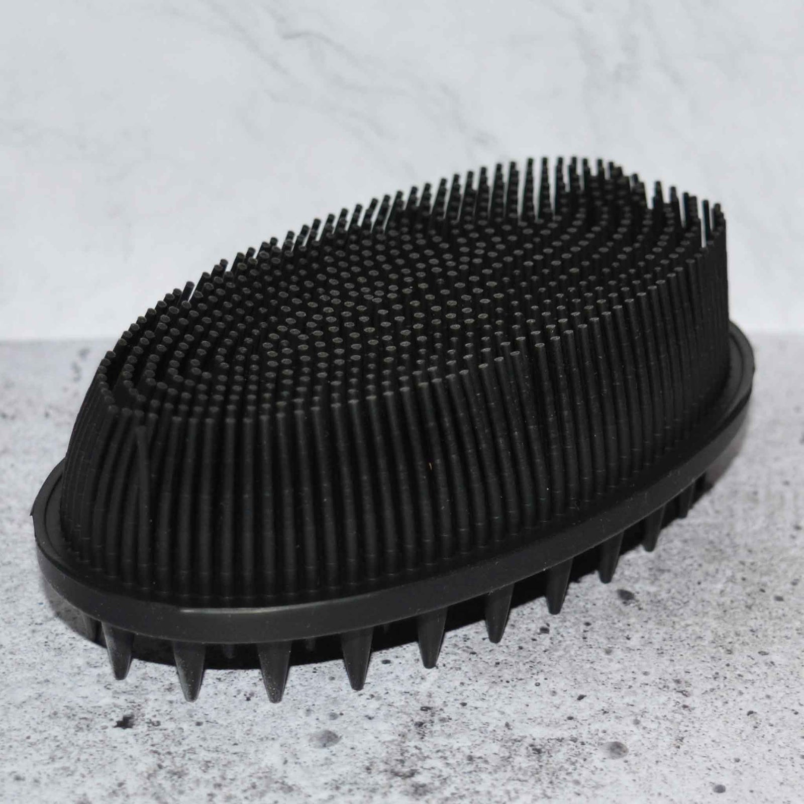 Black soft silicone scrub brush with very soft fine bristles on one side, and short firm nubs on the other side