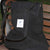 A black corduroy tote bag with long handles on a background of a park bench