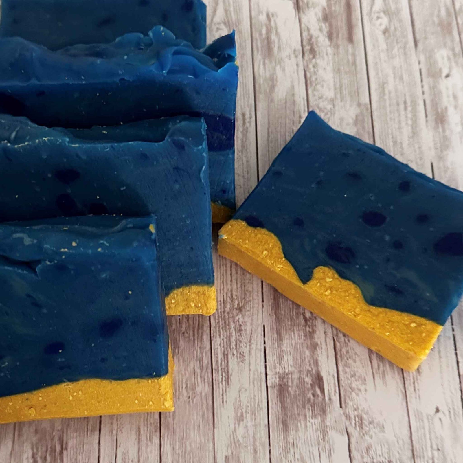 A row of Showalux blue and yellow soaps, and one soap laying flat on a white wash background