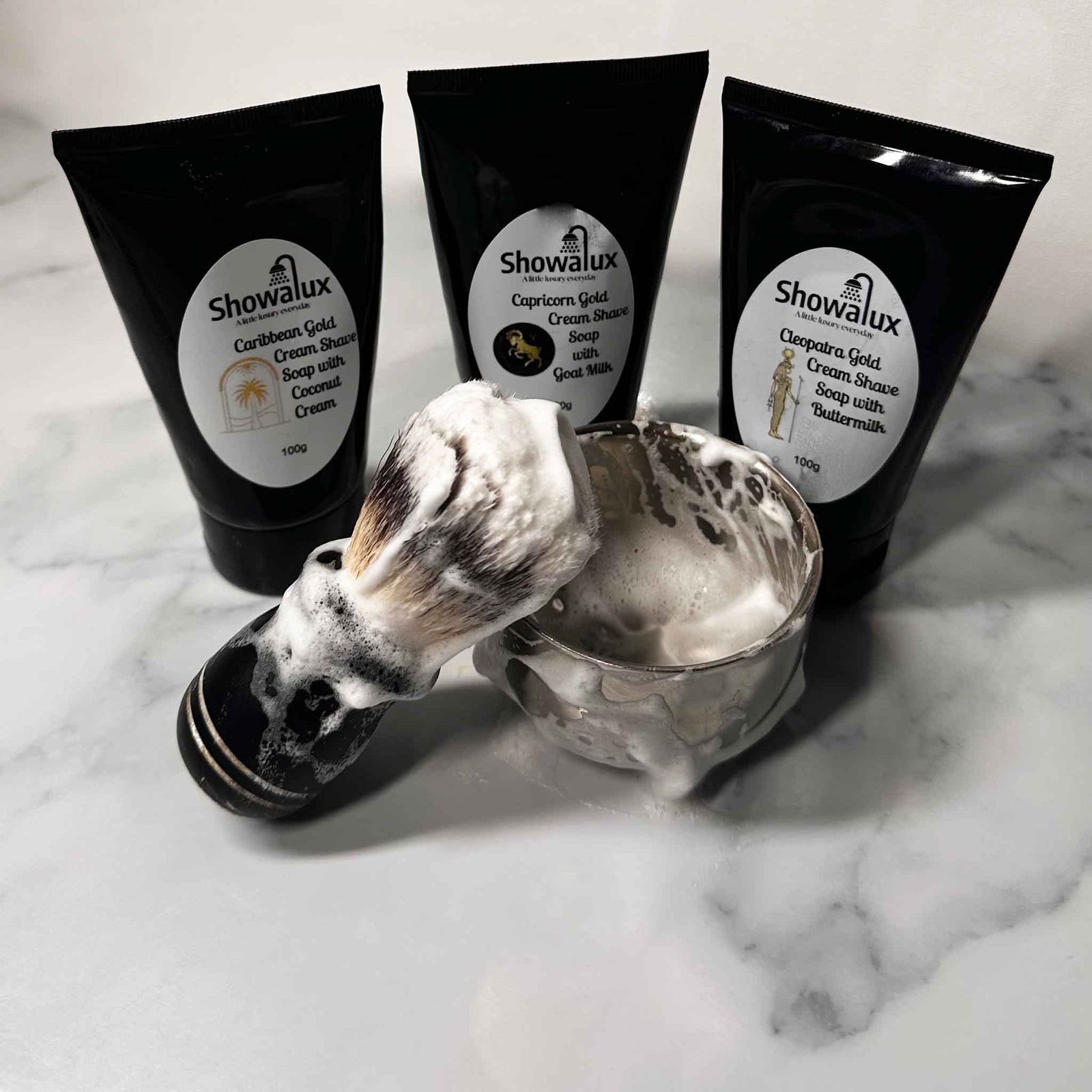 Showalux Cleopatra Gold Cream Shave Soap with Buttermilk on a marble surface with a shaving brush.